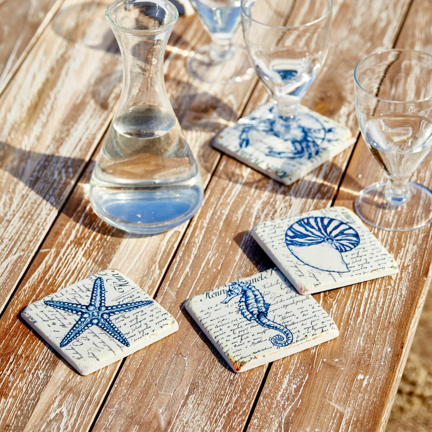 Onderzetter set van 4 Faune Marine Keramische onderzetters met blauwe zee-motieven op houten tafel, stijlvolle tafeldecoratie