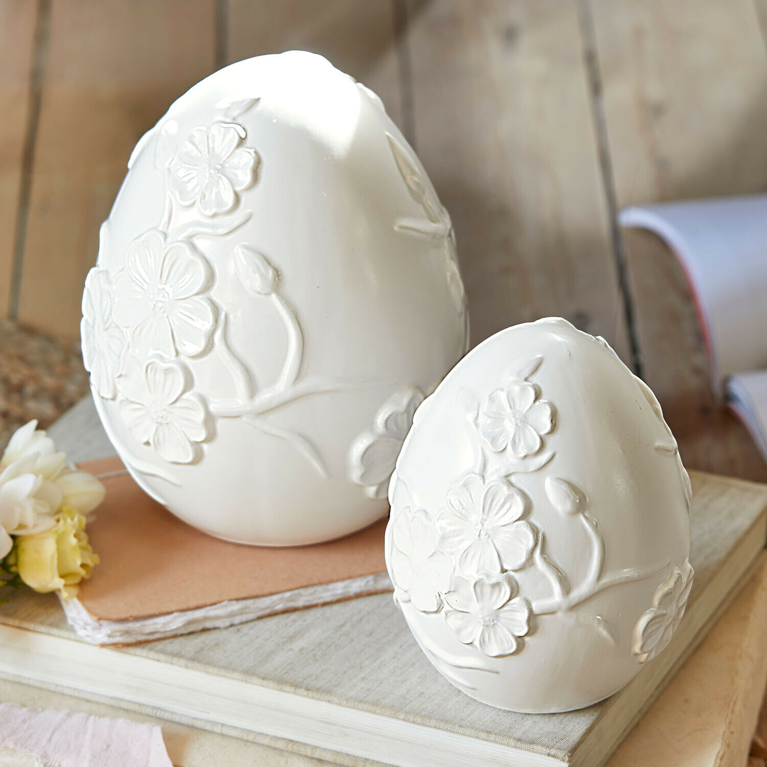 Witte keramische decoratieve eieren met reliëf bloemenmotief op boeken, lentebehang