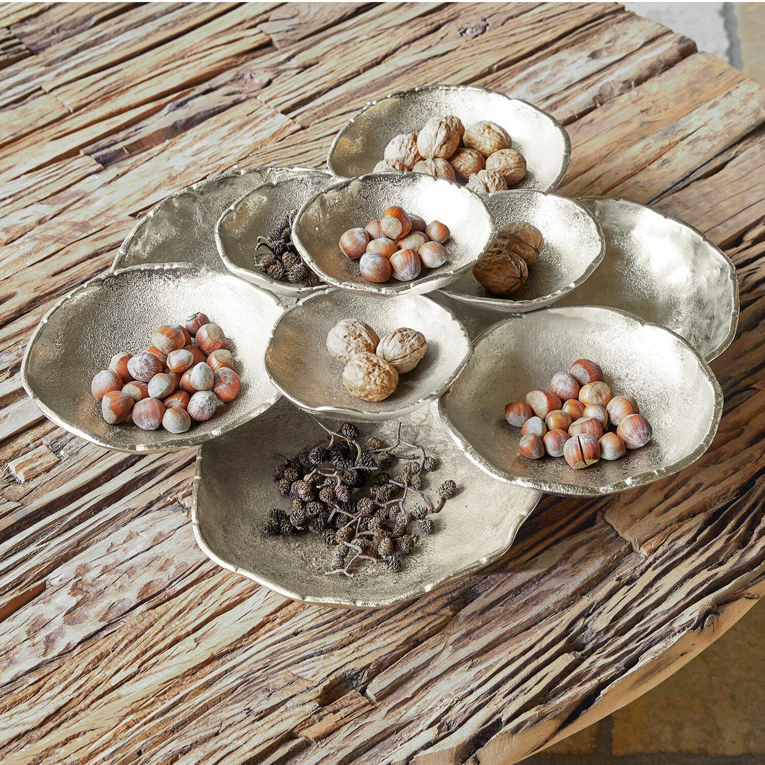 Decoratieve zilverkleurige metalen schaal met noten en gedroogd fruit op rustieke houten tafel