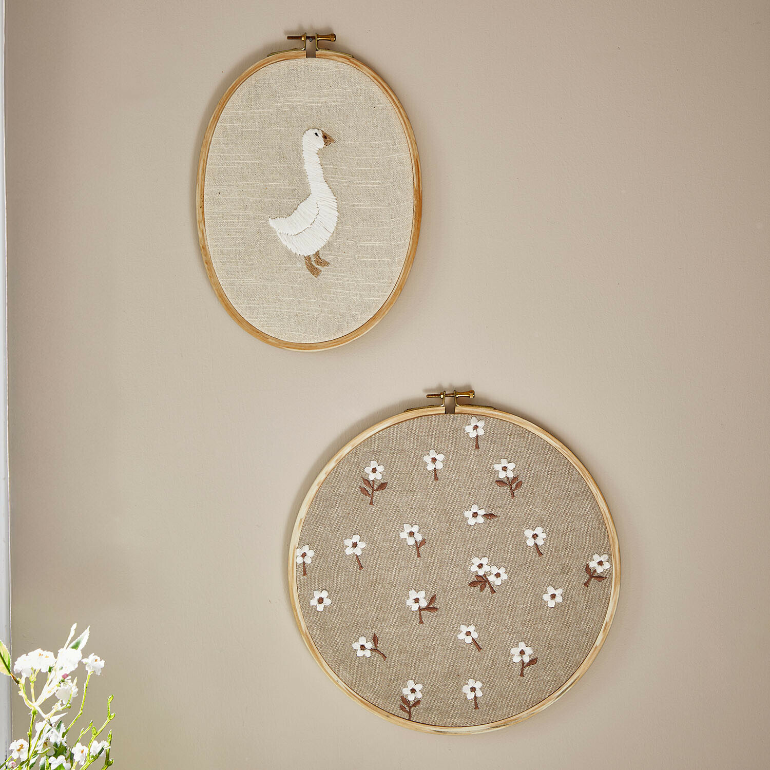 Twee geborduurde borduurringen van natuurlijk linnen met witte gans en bloemenpatroon aan de muur