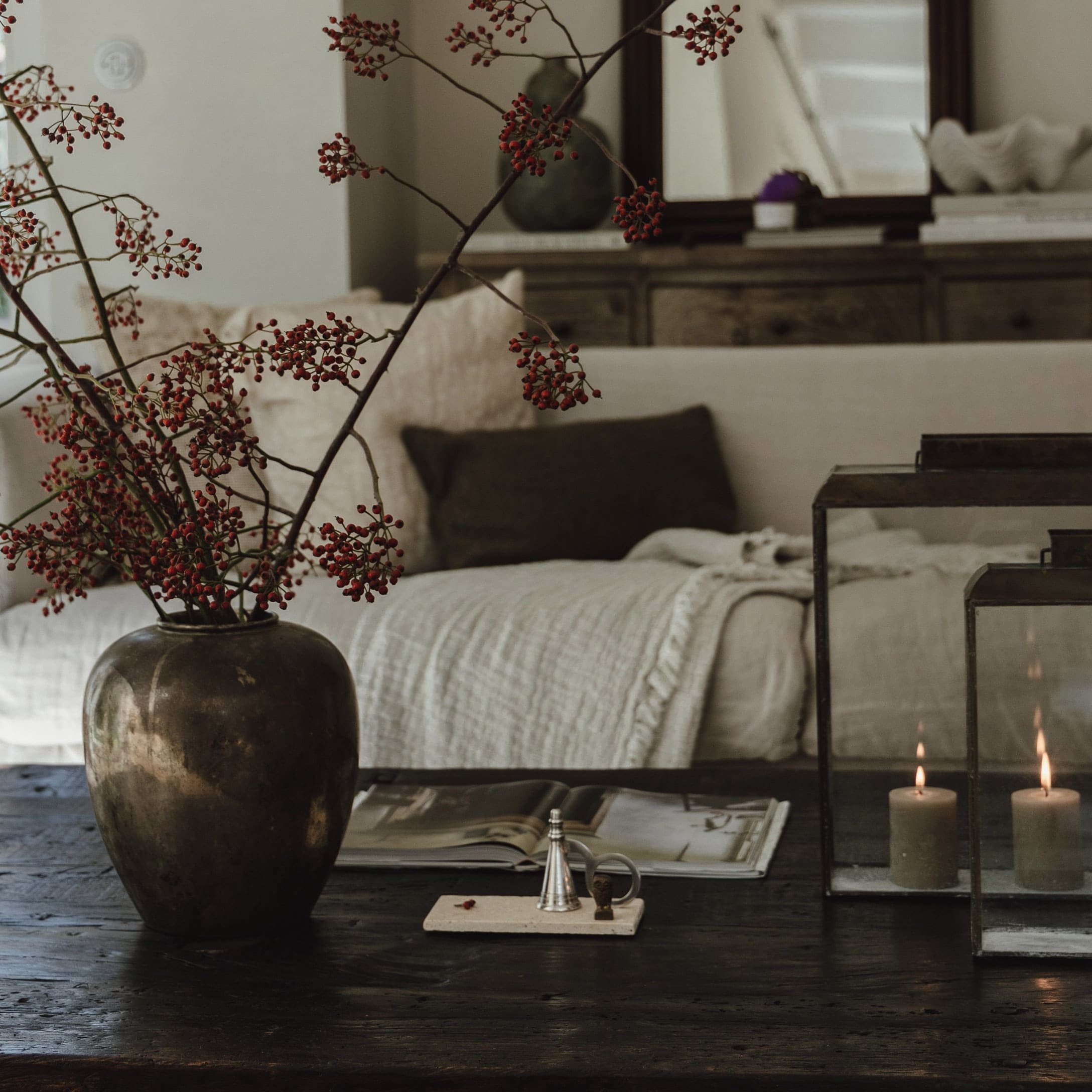Decoratieve vaas met rode takken op donkere houten tafel in gezellige woonkamer