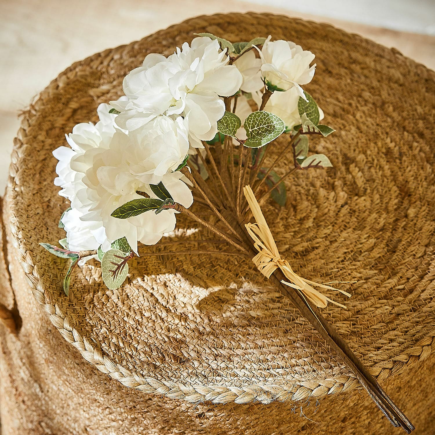 Sierboeket Quérisse Boeket witte kunstbloemen met groene bladeren op natuurlijke gevlochten jute achtergrond