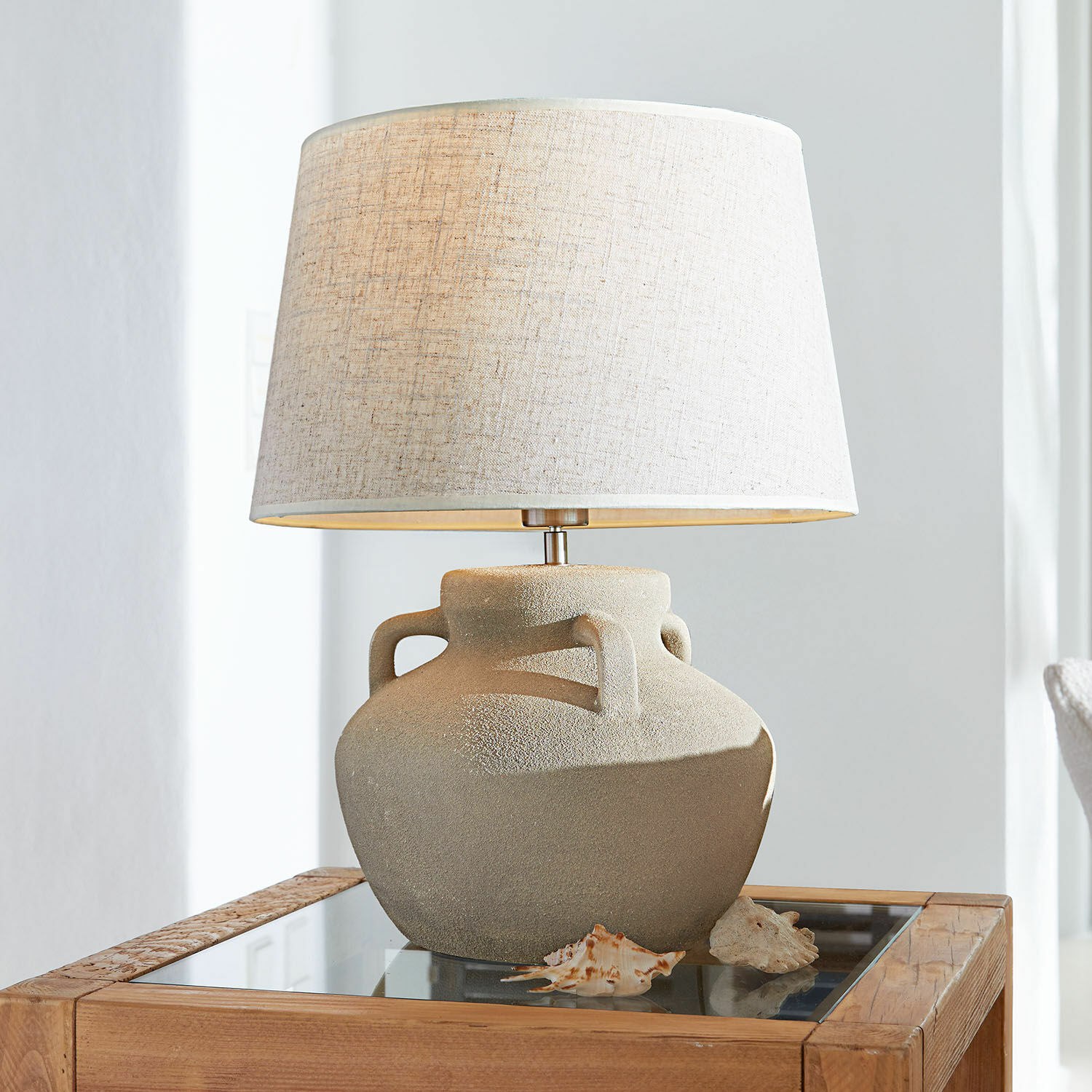 Tafellamp Parya Tafellamp met beige keramische voet en lichte kap op houten tafel