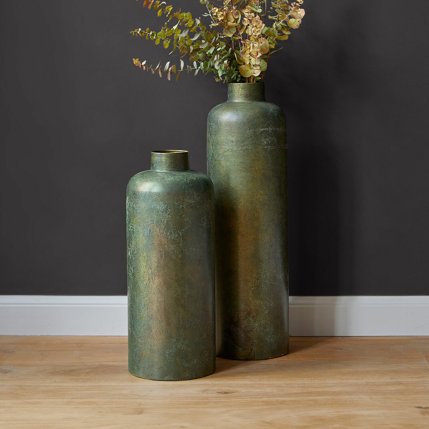 Set van twee grote groene metalen vazen met verouderde look op houten vloer