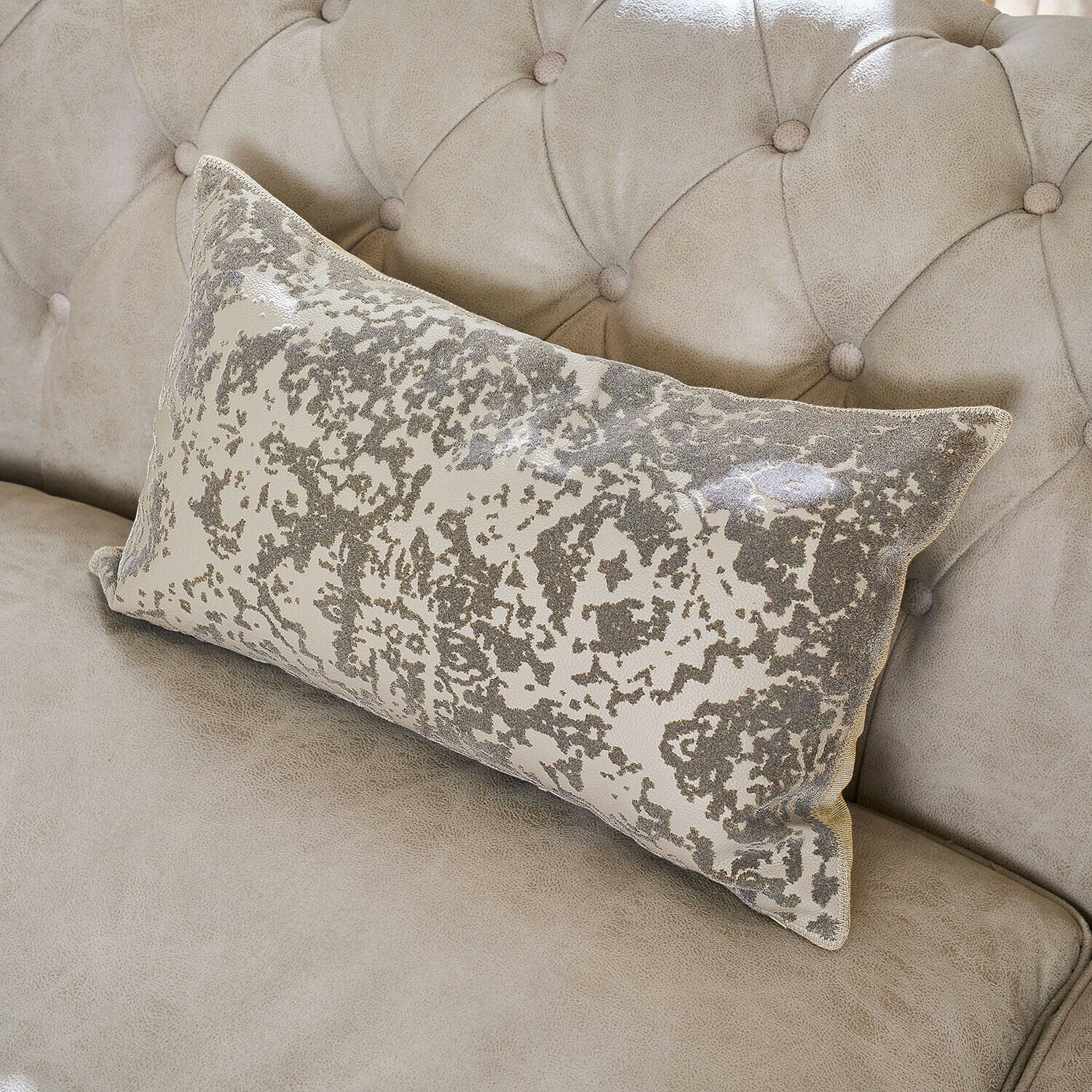 Rechthoekig sierkussen met grijs-beige patroon op lichtbeige gestoffeerde bank