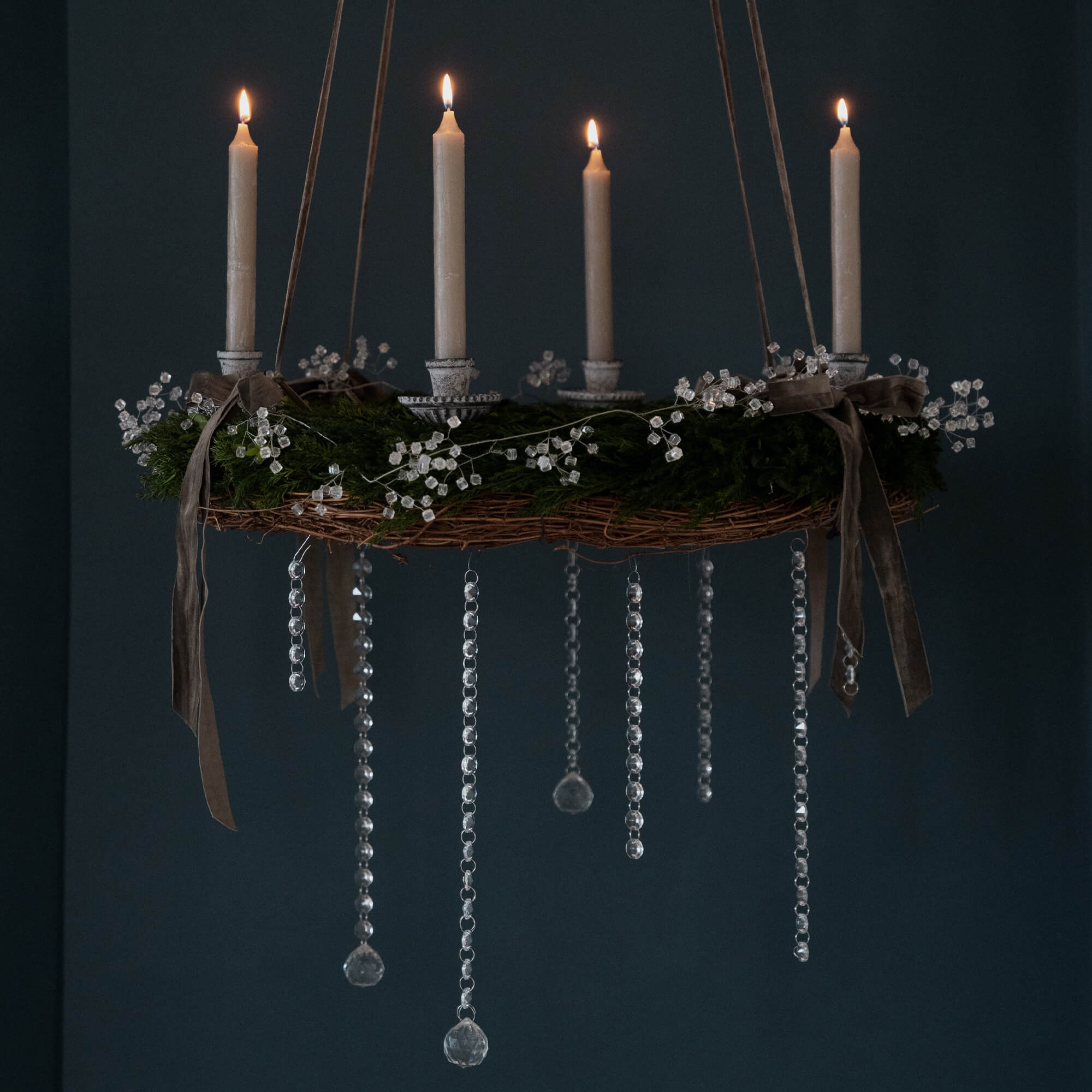 Hangende adventskrans met groene takken, witte kaarsen en kristallen versieringen voor kerst