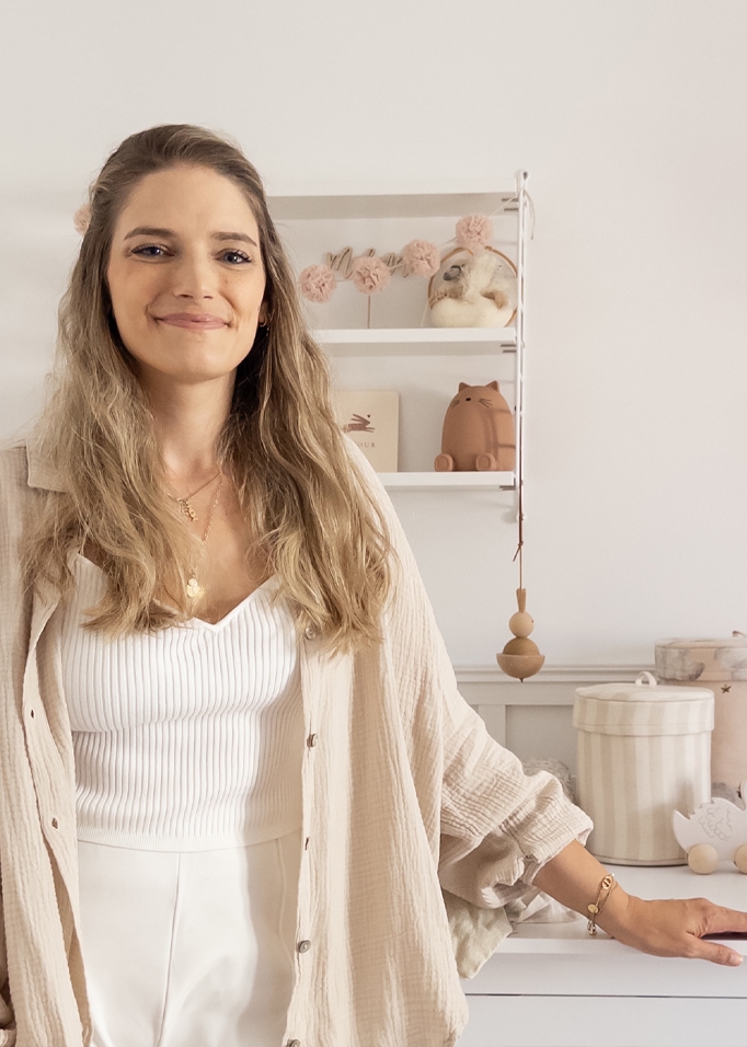 Vrouw in wit topje en beige blouse in lichte kamer met kinderdecoraties
