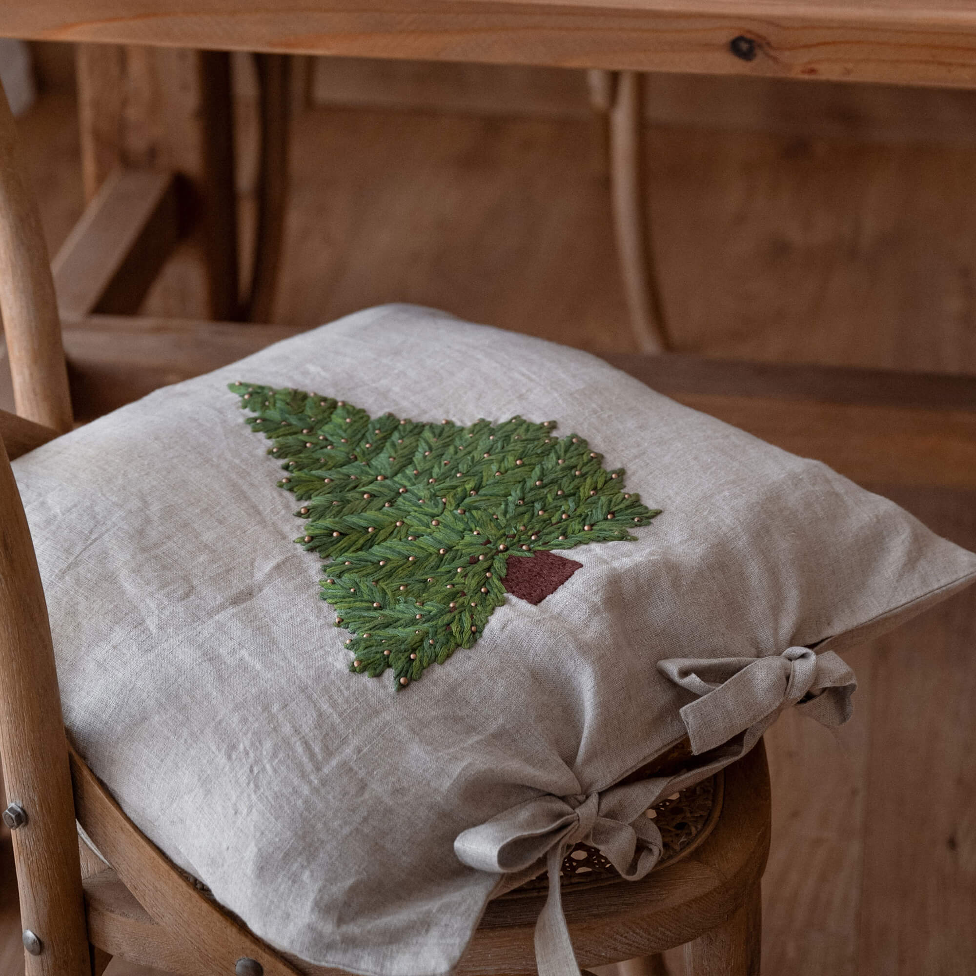 Beige linnen kussenhoes met geborduurde groene kerstboom en decoratieve strikken