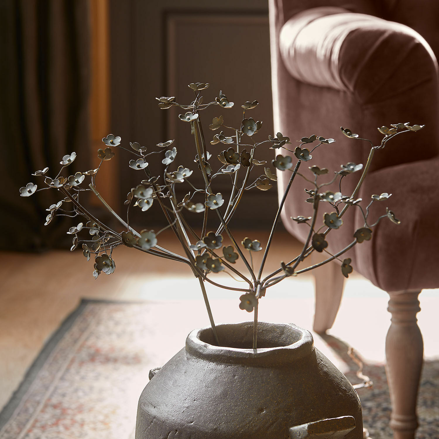 Sierbloem set van 2 Basmirah Decoratieve metalen tak met bloemen in een grijze keramische vaas op een tapijt in de woonkamer