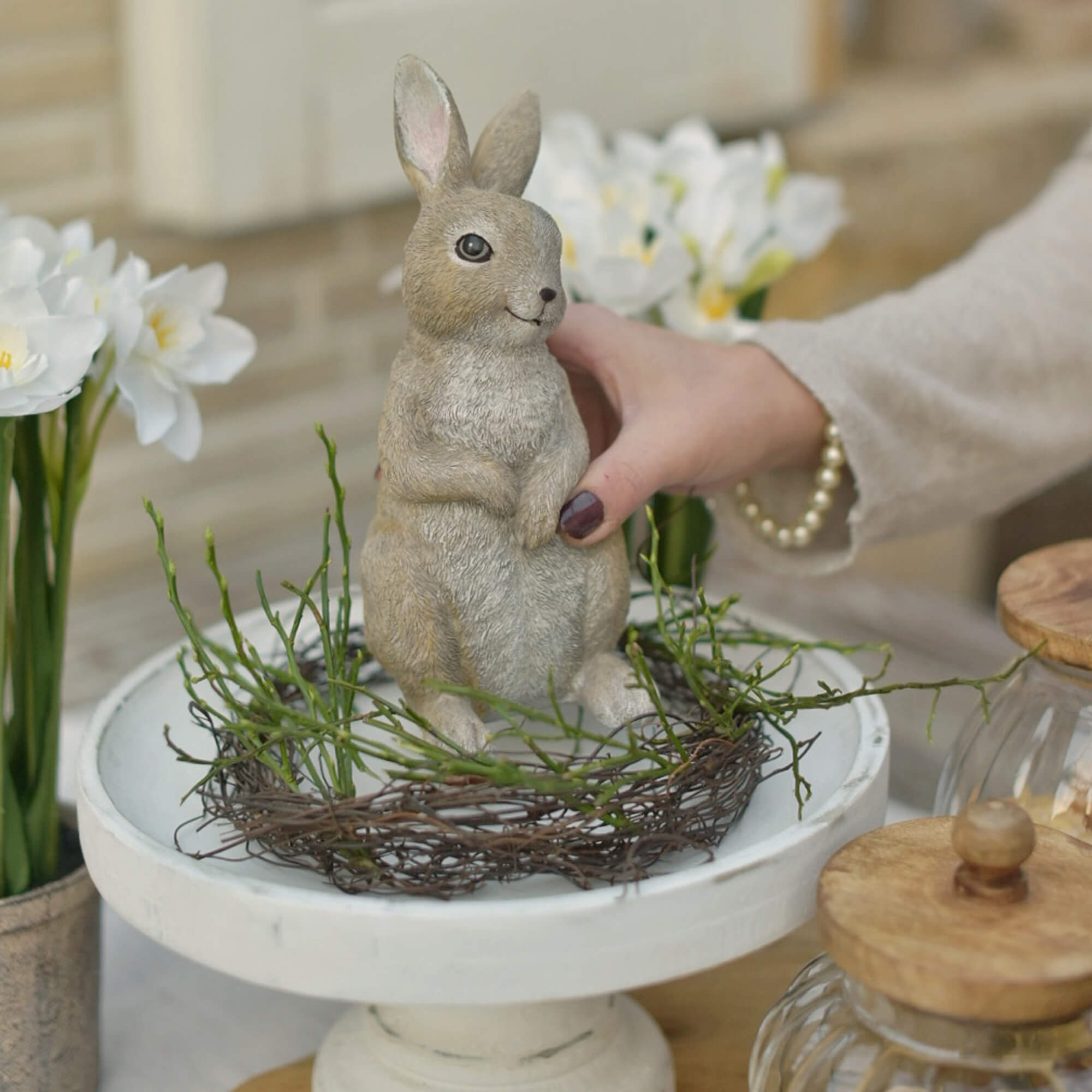 Paasdecoratie konijn in natuurlijke kleuren op witte standaard met groene takken