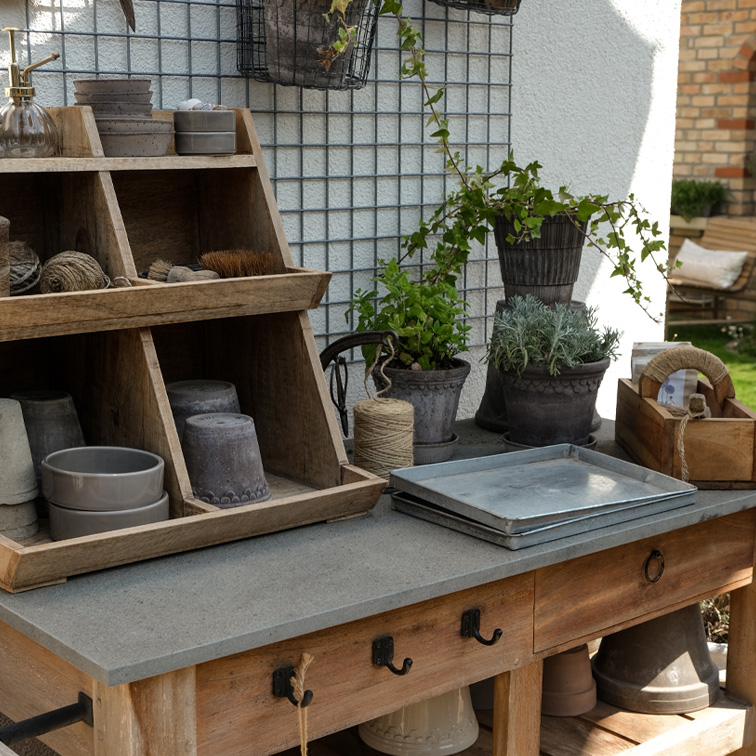 Houten tuintafel met plantgereedschap en bloempotten in natuurlijke kleuren, tuinopstelling