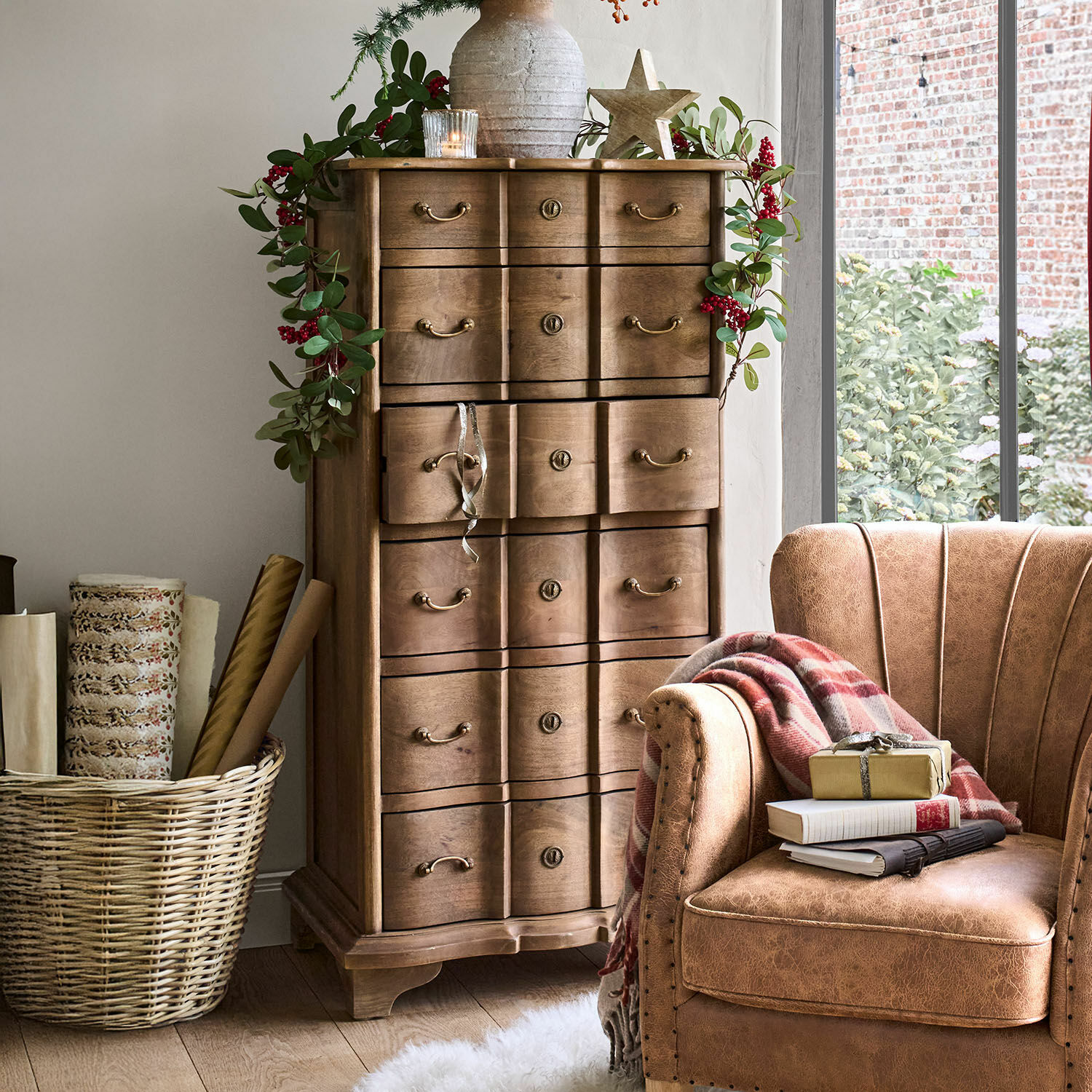 Ladekast Aiguillon Houten ladekast met decoratieve handgrepen en groene bladguirlande met rode bessen in een gezellige kamer