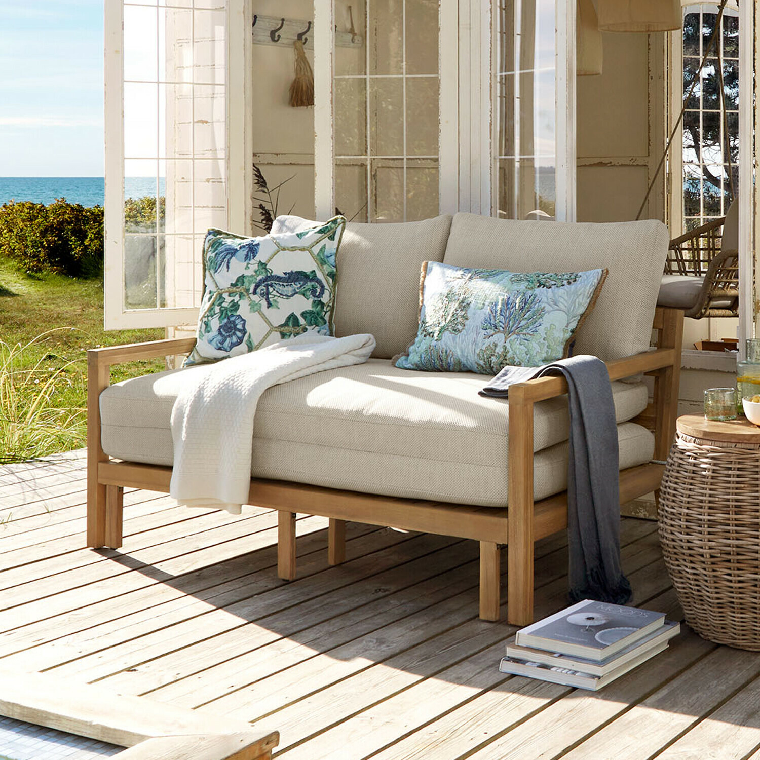 Uitschuifbare bank Tjorna Lichtbeige bank met houten frame op terras met uitzicht op tuin en zee