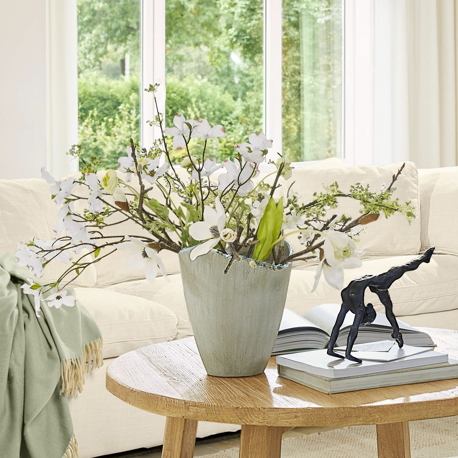 Grijze keramische decoratieve vaas met witte bloemen op houten tafel in lichte woonkamer