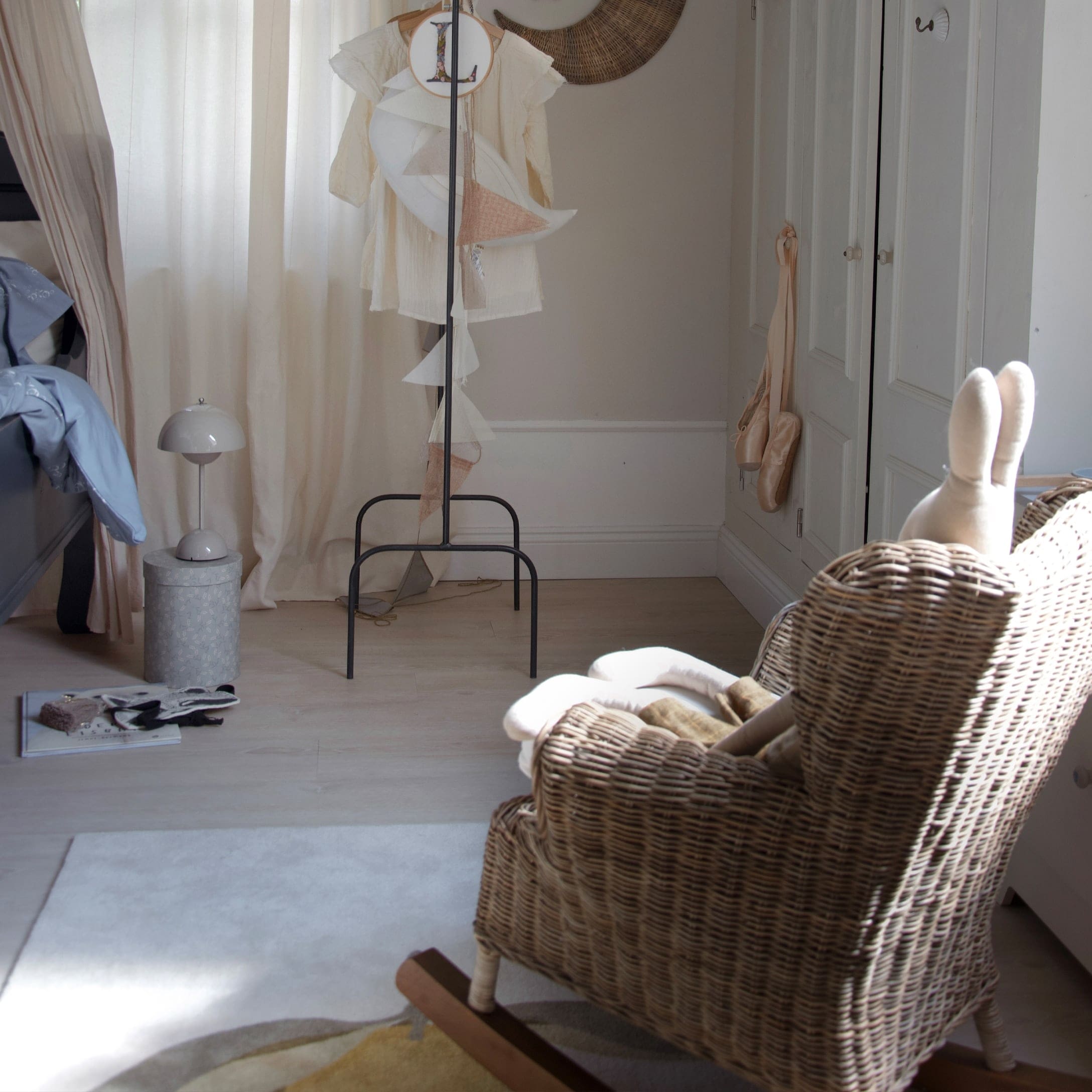 Kinderkamer met rotan schommelstoel en lichte gordijnen, gezellige en lichte inrichting