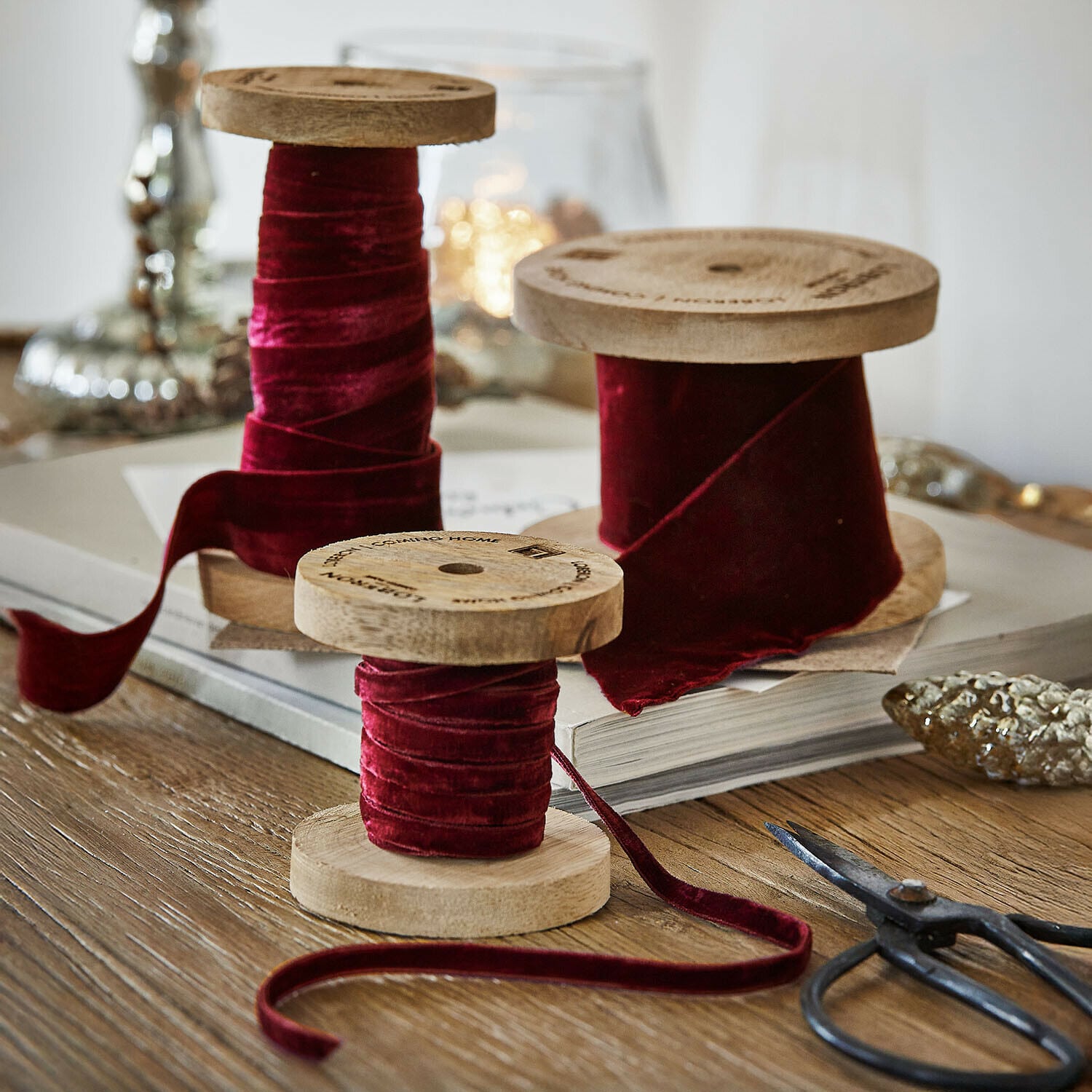 Fluwelen lint set van 2 Liandis Drie houten spoelen met bordeauxrode fluwelen lint op houten tafel met decoratieve schaar