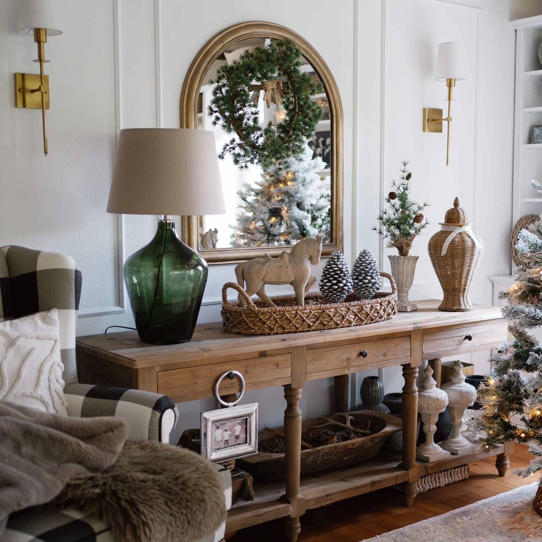 Houten tafel met kerstdecoratie, groene lamp en spiegel met krans in gezellige woonkamer