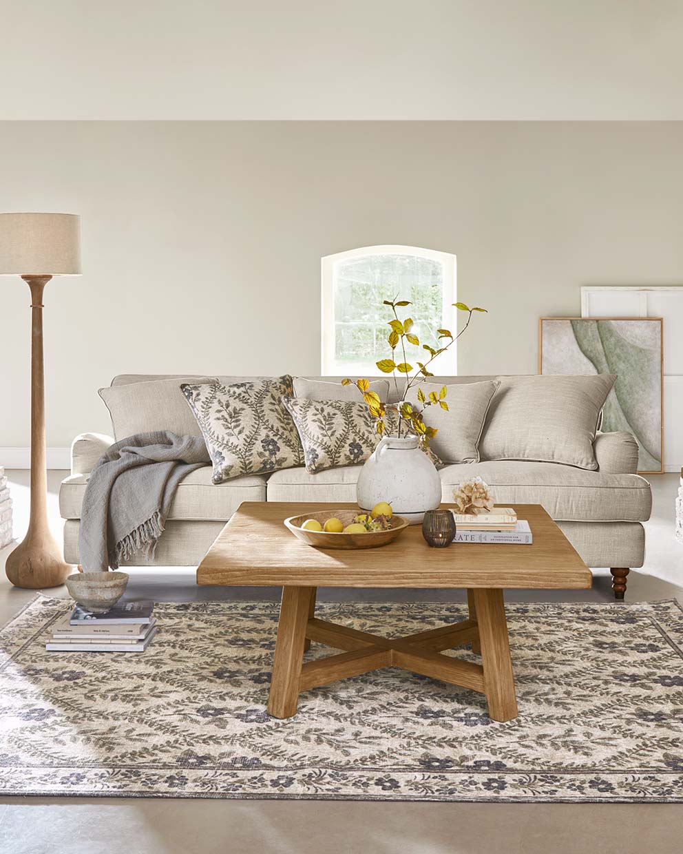 Beige bank met kussens en houten salontafel op patroon vloerkleed in gezellige woonkamer