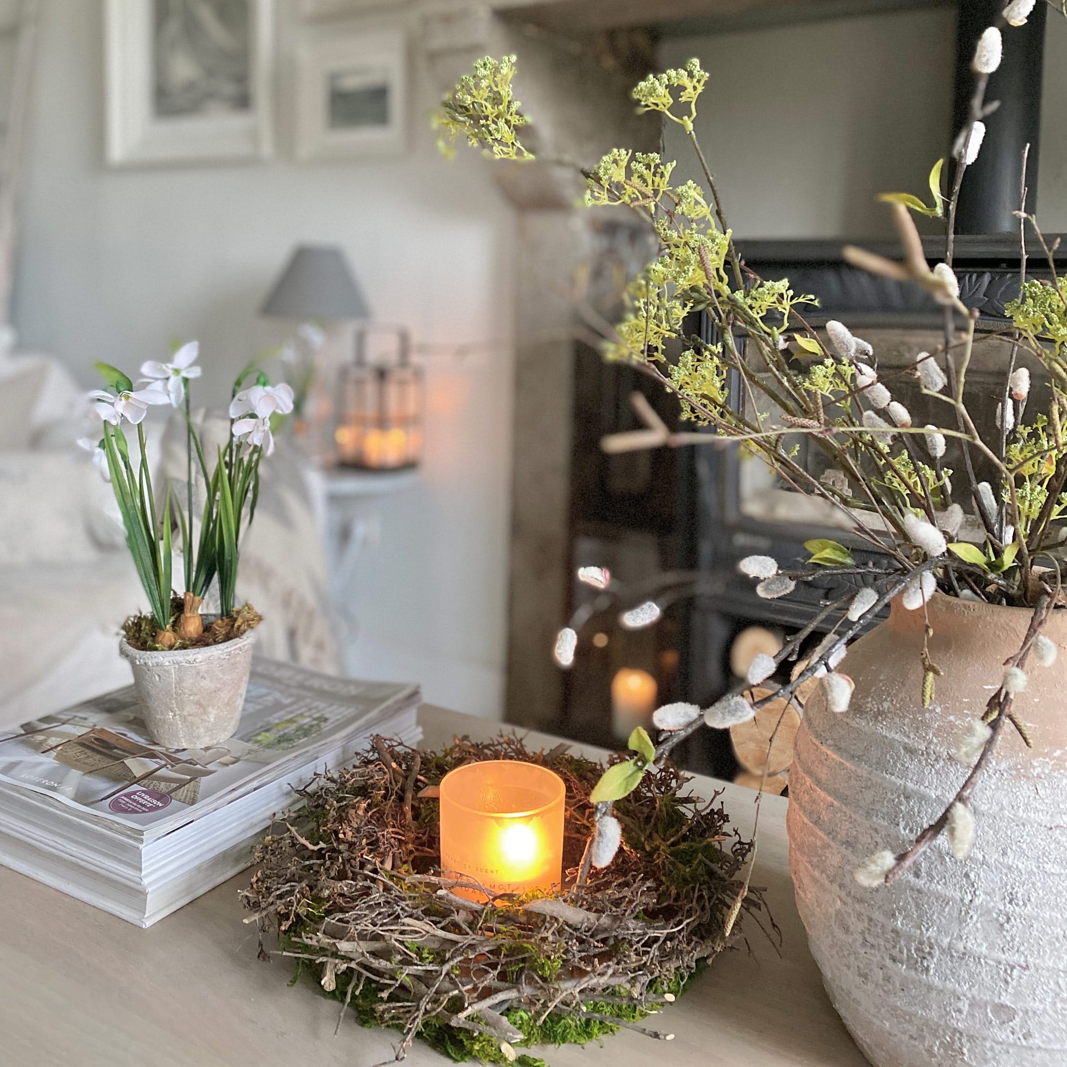Decoratieve krans van takken met kaars in glazen houder op tafel in lichte kamer