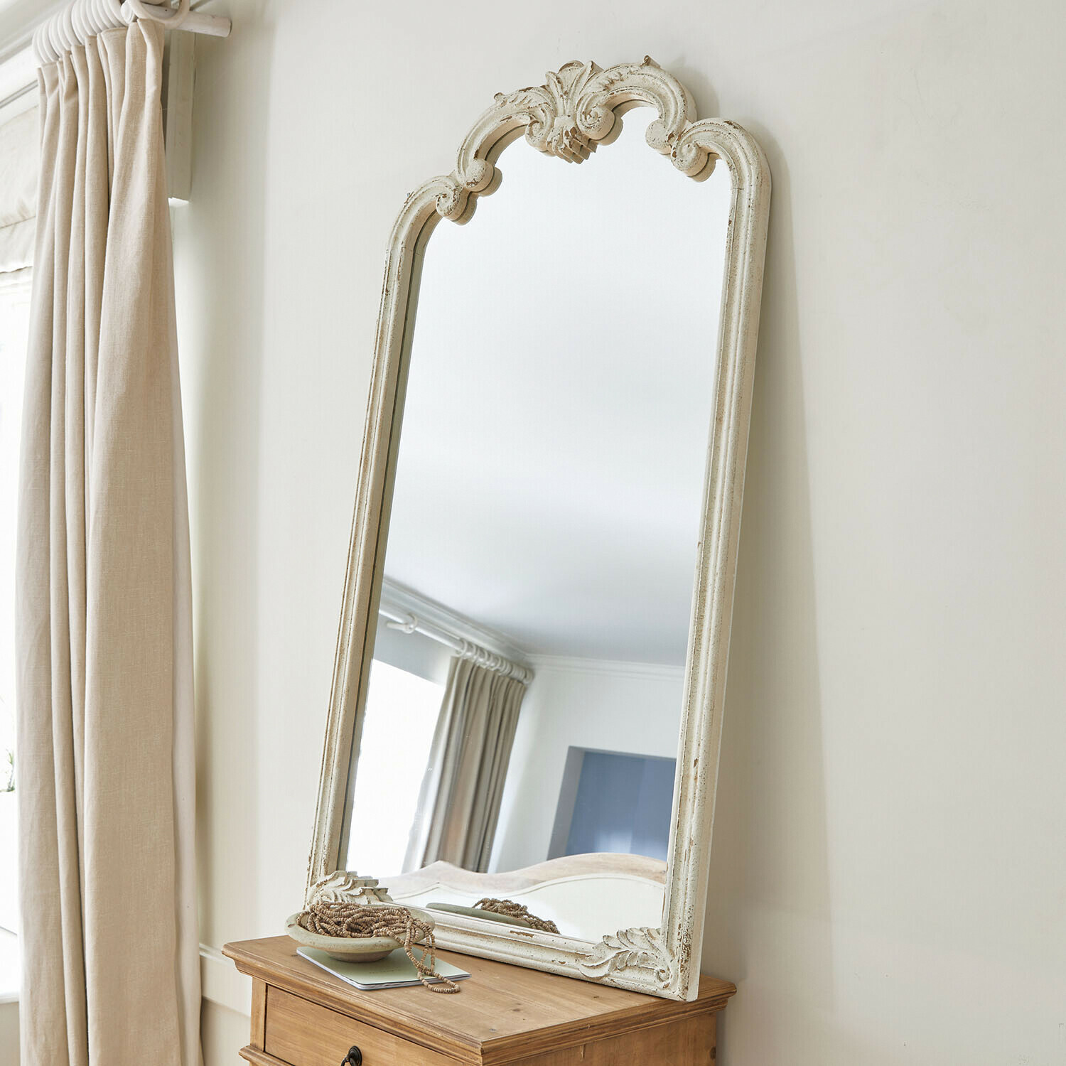 Staande spiegel met witte, verweerde houten lijst en decoratief patroon in vintage stijl