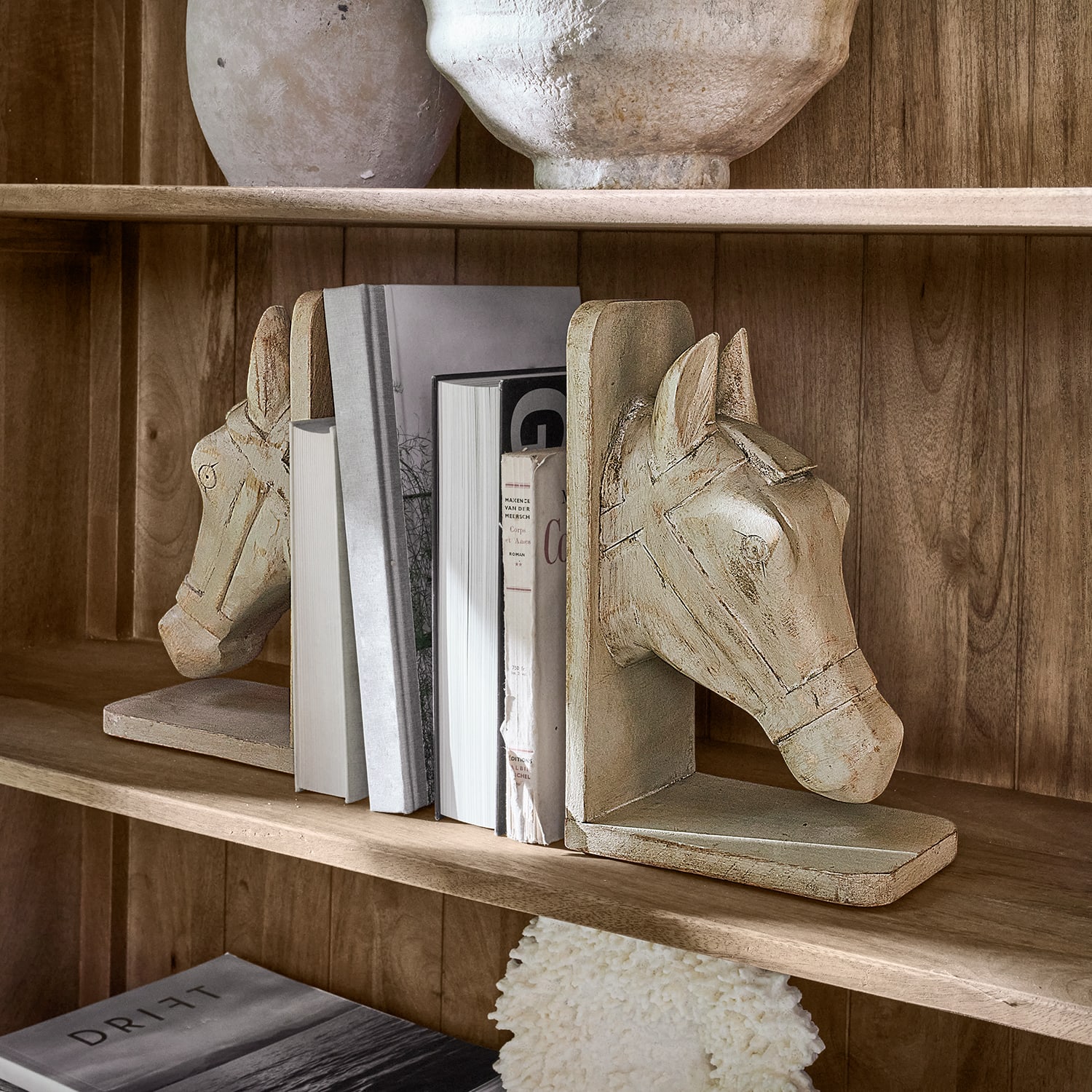 Set beige houten boekensteunen met paardenhoofdmotief op houten plank met boeken