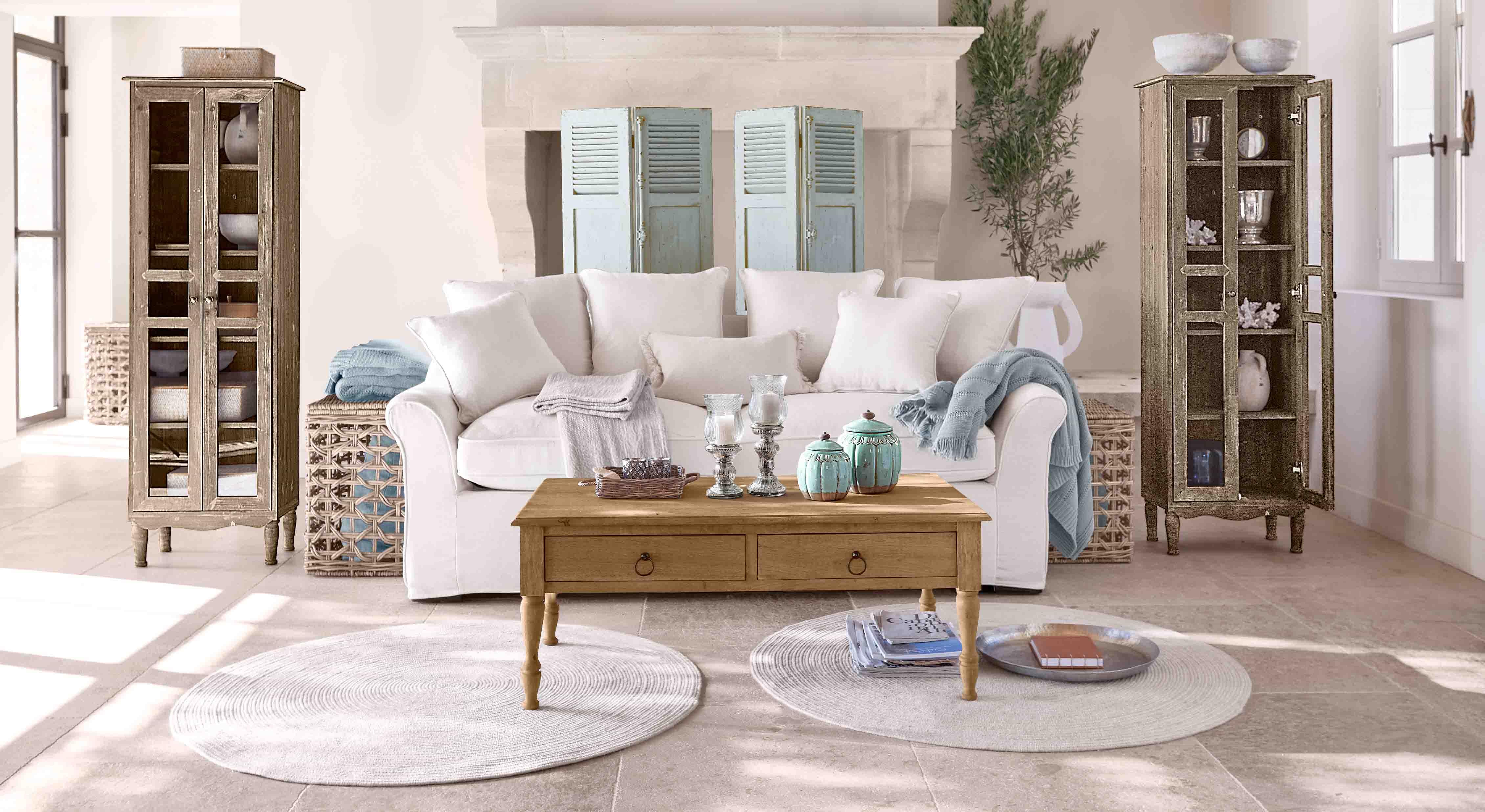Gezellige woonkamer met witte bank, houten salontafel en twee vintage houten vitrinekasten