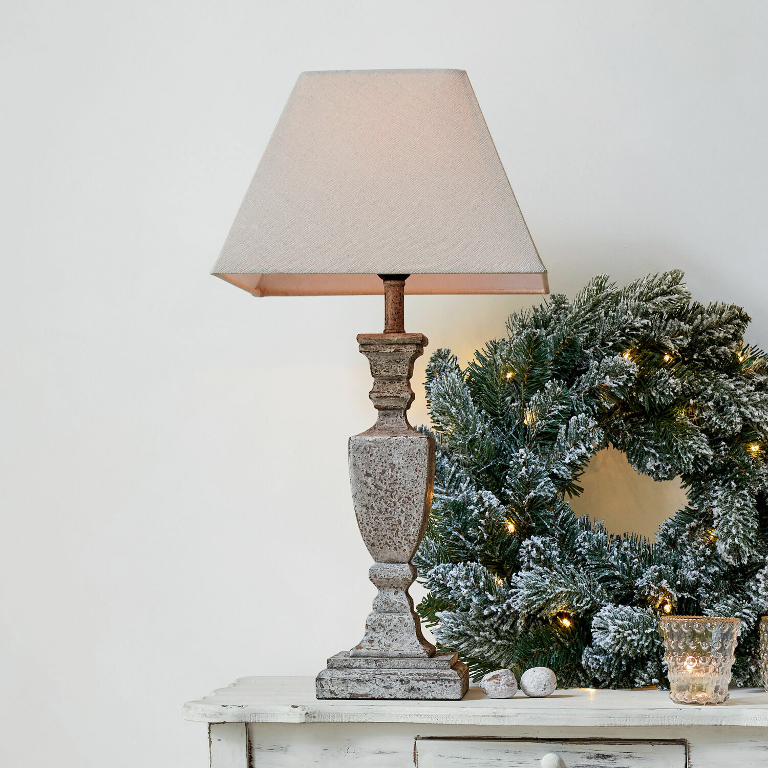Tafellamp Gorham Beige stenen tafellamp met kap naast groene kerstkrans met lichtjes op witte tafel