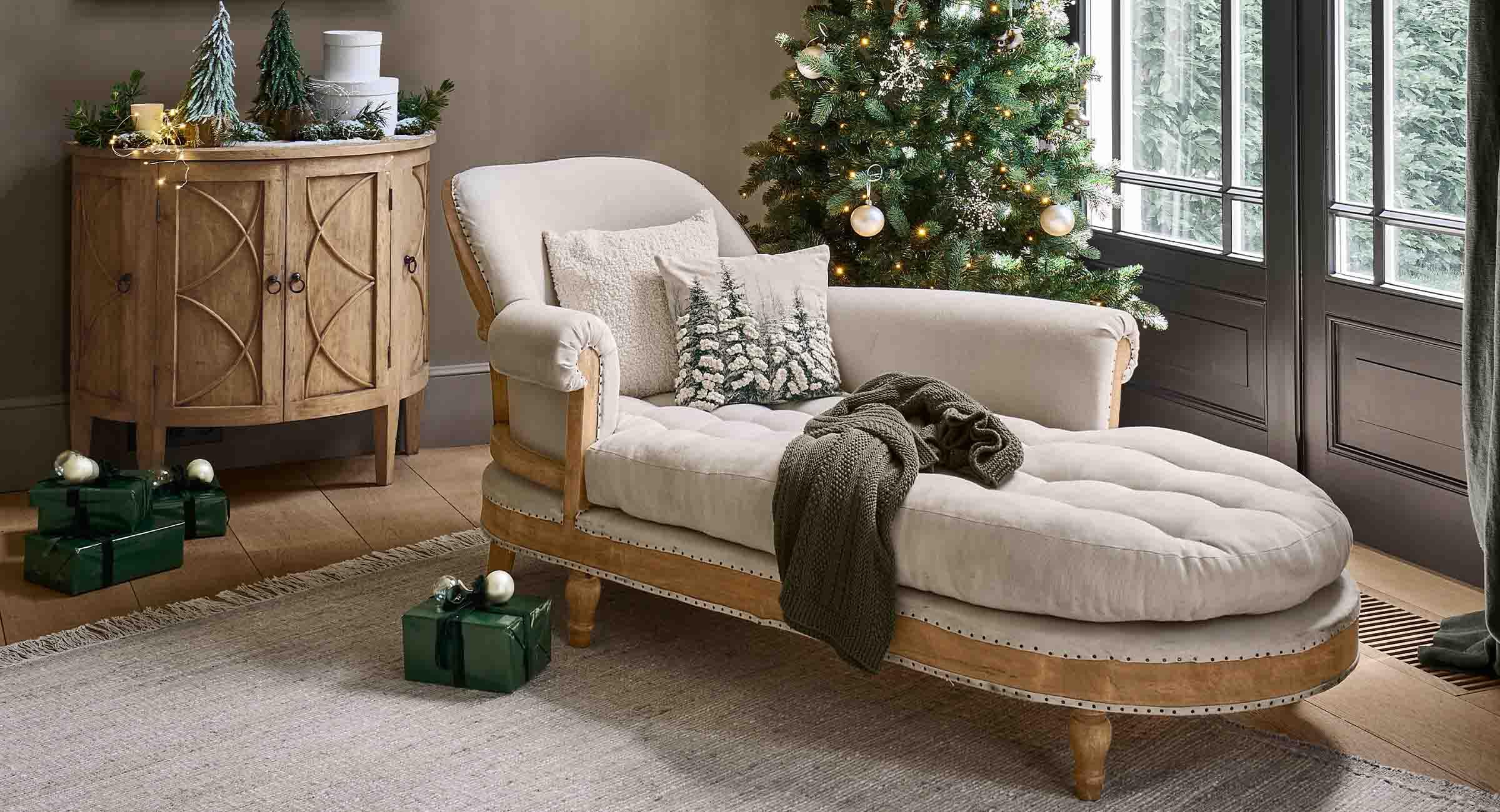 Gezellige woonkamer met beige gestoffeerde chaise longue, houten kast en versierde kerstboom met lichtjes