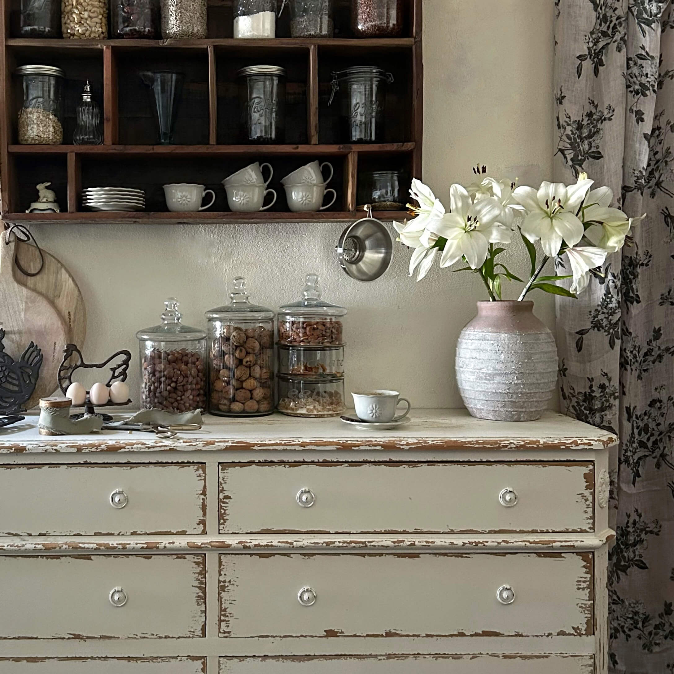 Rustieke witte ladekast met roze keramische vaas en witte lelies in vintage keuken