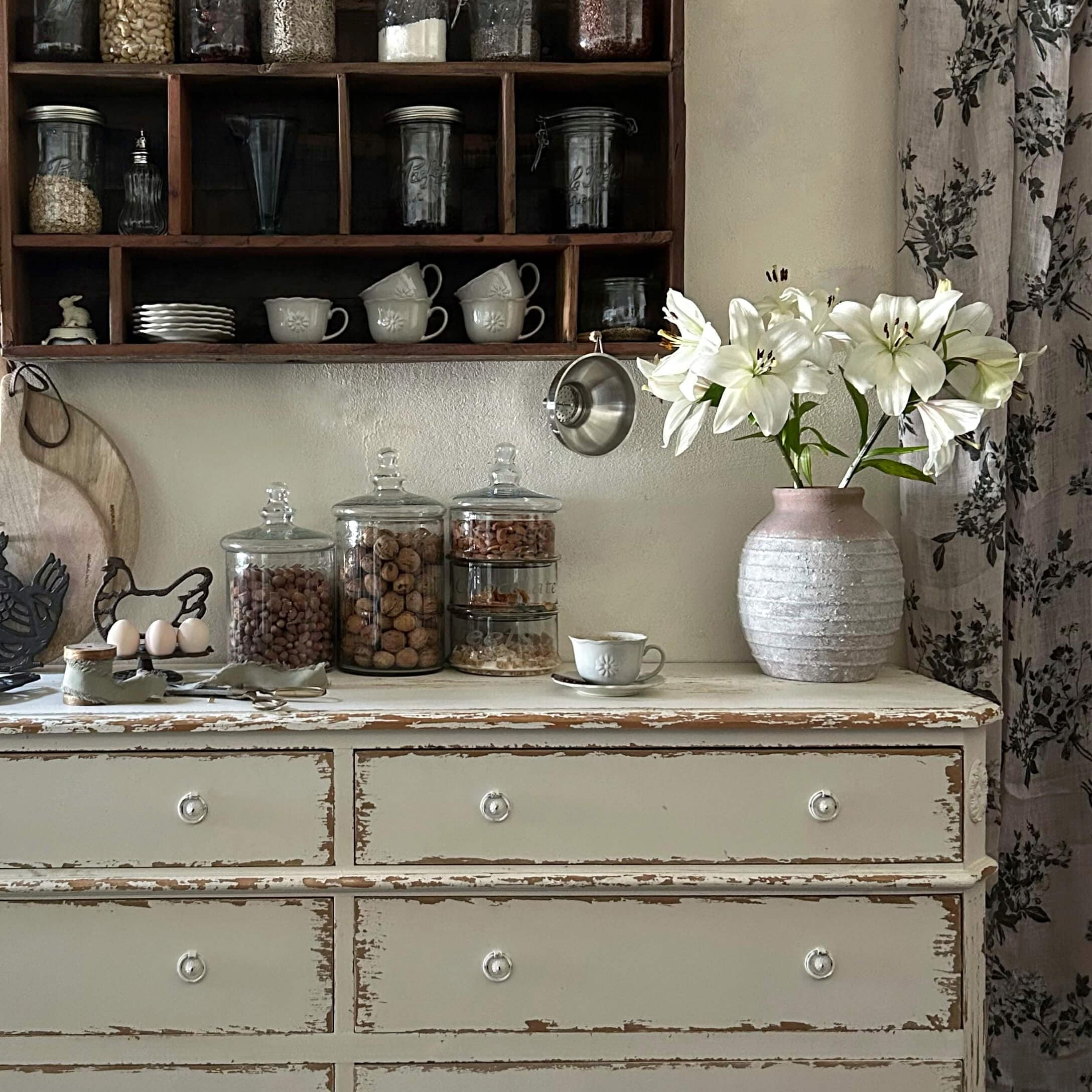 Rustieke witte ladekast met roze keramische vaas en witte lelies in vintage keuken