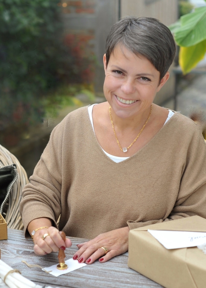 Vrouw in beige trui met kort haar gebruikt zegel op cadeaupakket op houten tafel