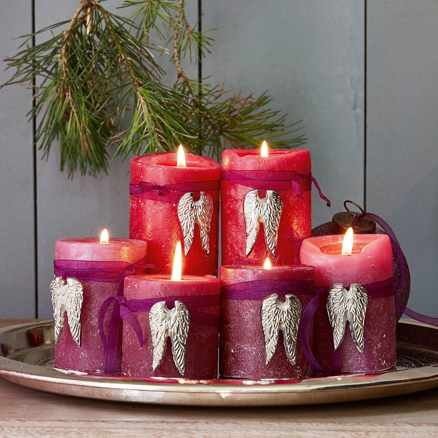 Set rode en roze kaarsen met metalen vleugels op een decoratieve zilveren schaal