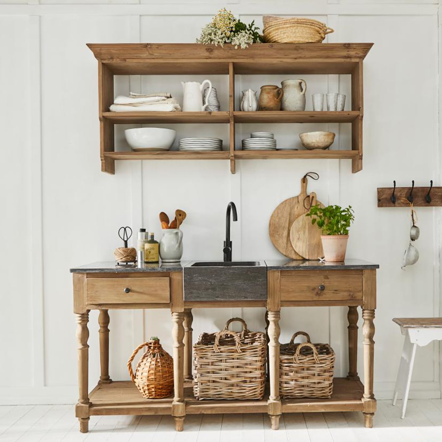 Rustieke houten keuken met zwarte gootsteen en rieten manden tegen witte muur