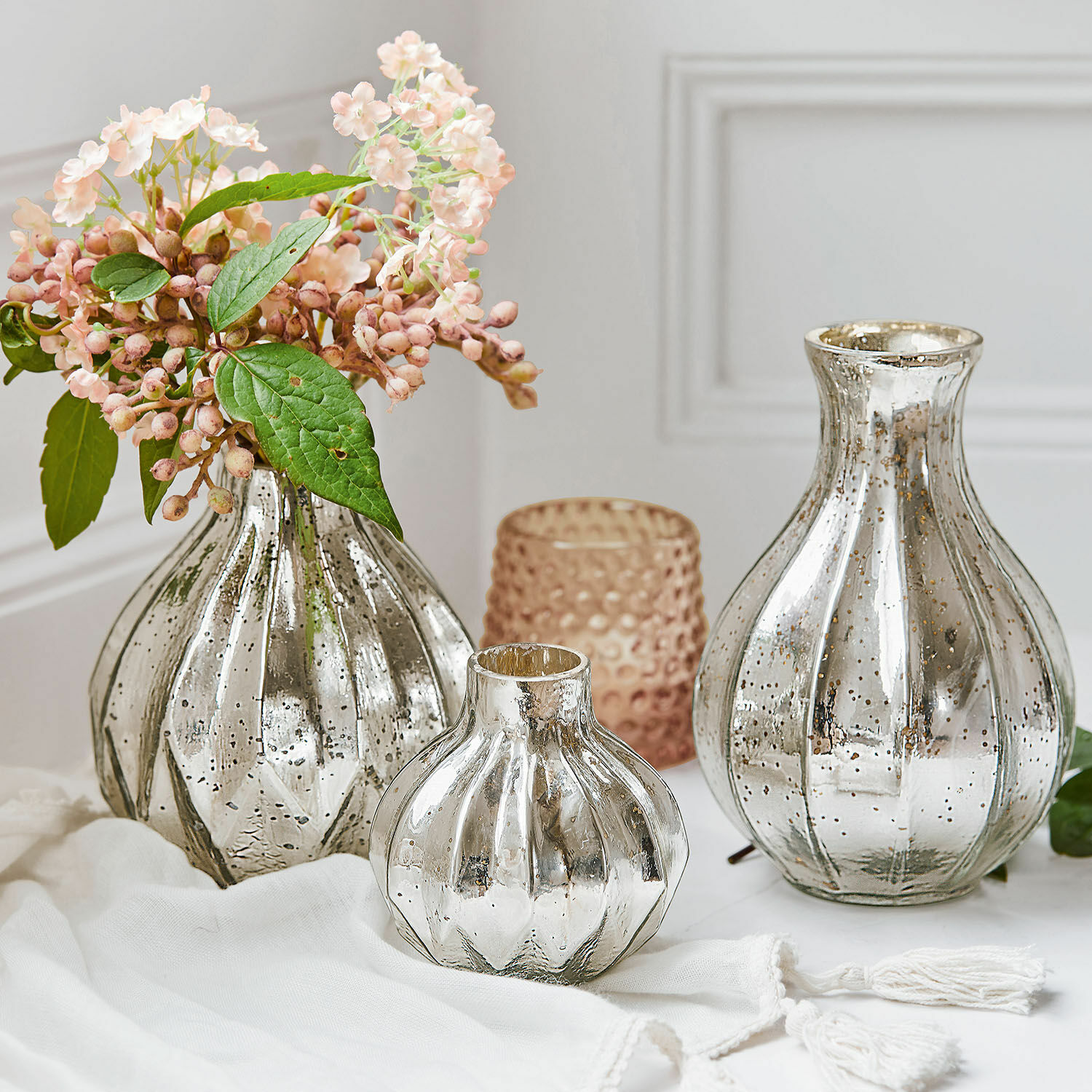 Drie decoratieve vazen van glas met verouderd zilver effect en bloemen op witte achtergrond