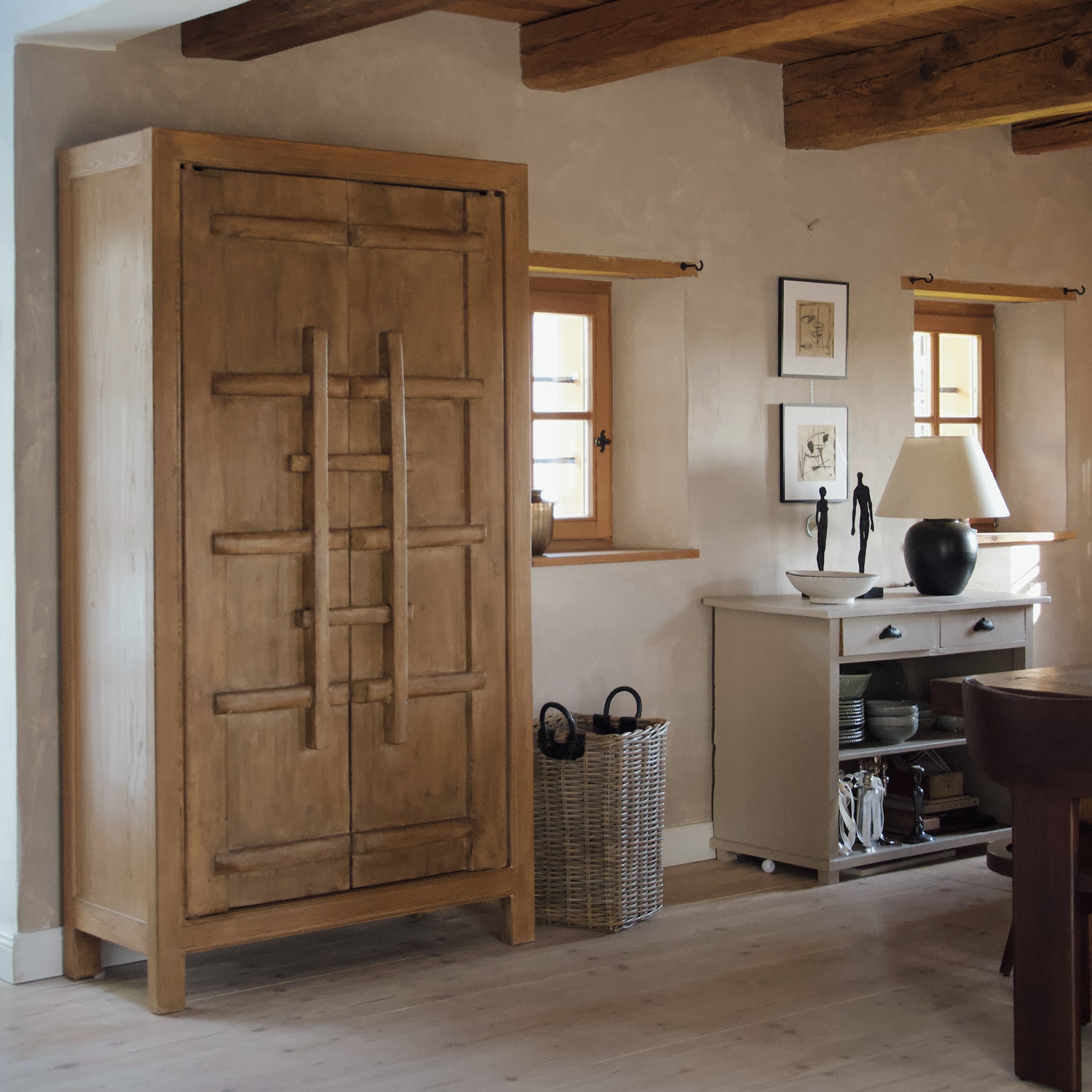 Houten kast in natuurlijke kleur in rustieke kamer met decoraties en zwarte tafellamp