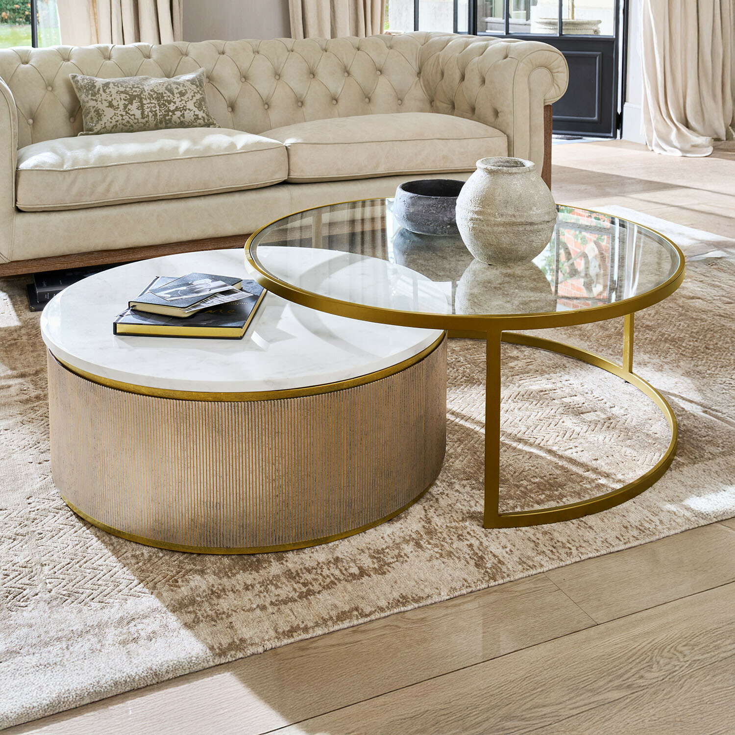 Set van twee salontafels met marmeren en glazen blad en gouden frame in lichte woonkamer