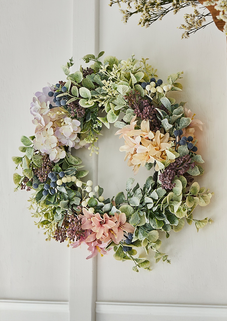 Decoratieve krans met pastelkleurige bloemen en groen blad, lente-decoratie voor deur