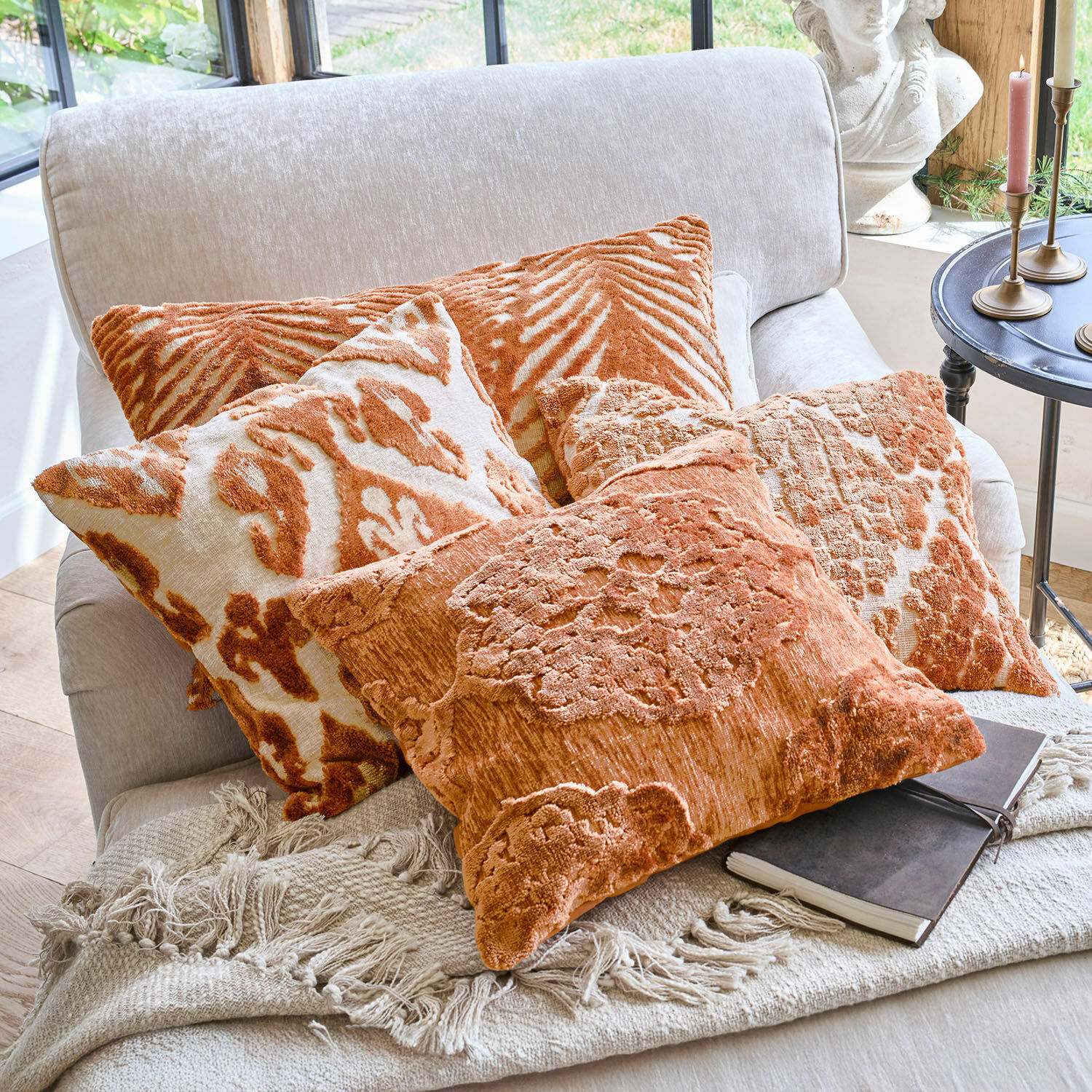 Set oranje sierkussens met patronen op een lichte bank met een gebreide deken