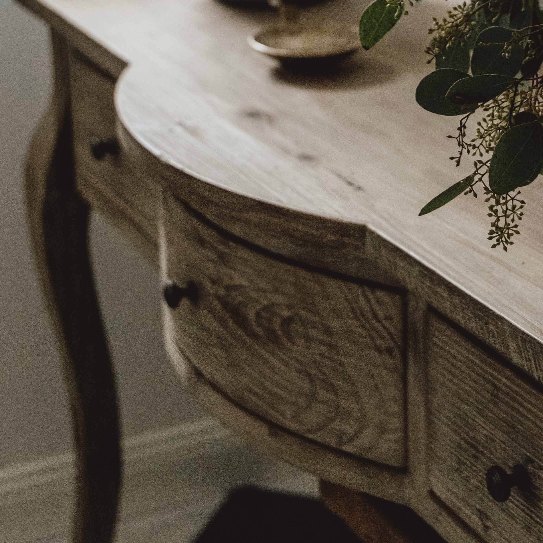 Houten tafel in natuurlijke kleur met lades en plantenversiering op het blad, woonkamermeubel