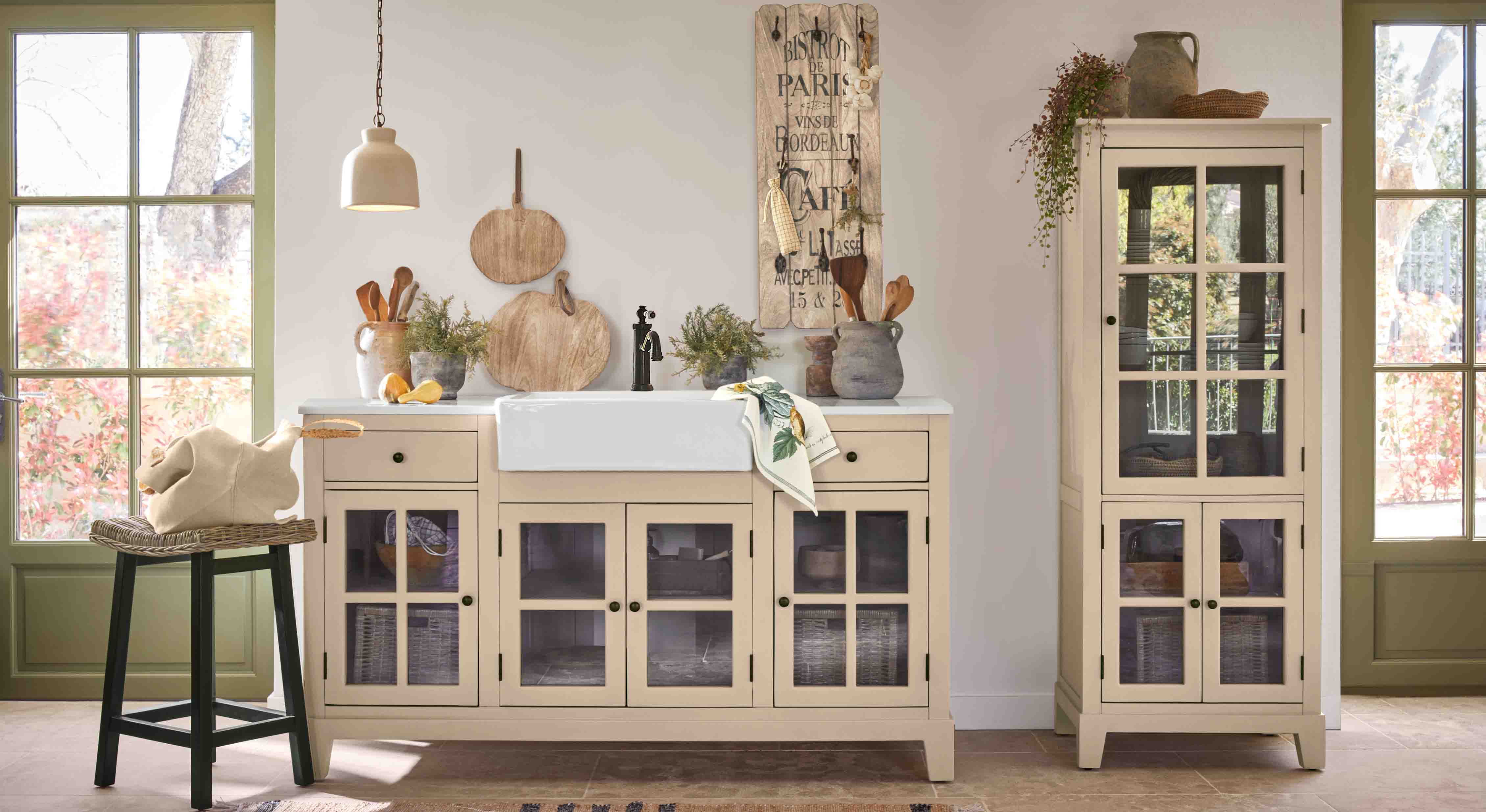 Rustieke keuken met beige vitrinekasten en witte keramische gootsteen, houten decoraties en planten