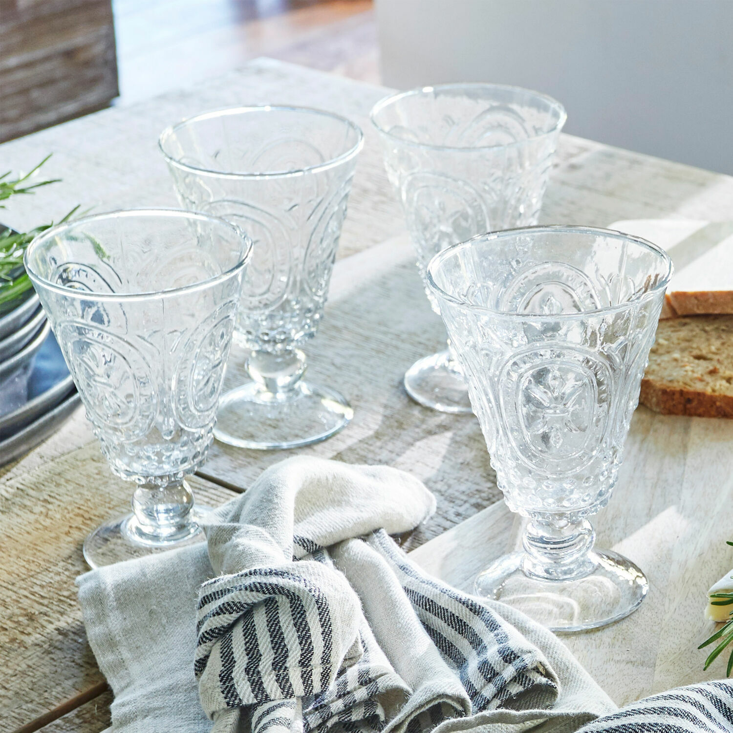 Wijnglas set van 4 Sarton Set van vier doorzichtige glazen met decoratief patroon op houten tafel met stof en brood