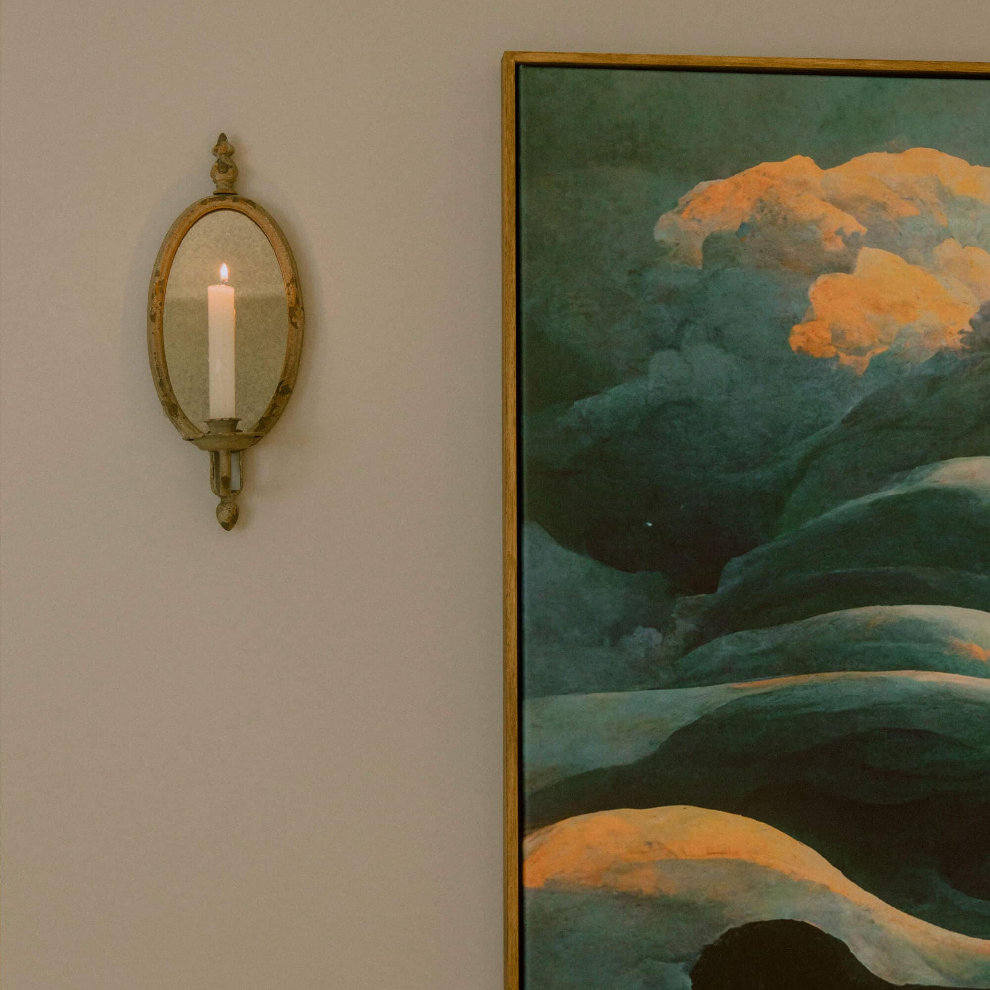 Ovale metalen wandkandelaar met spiegel en witte kaars aan beige muur voor interieurdecoratie