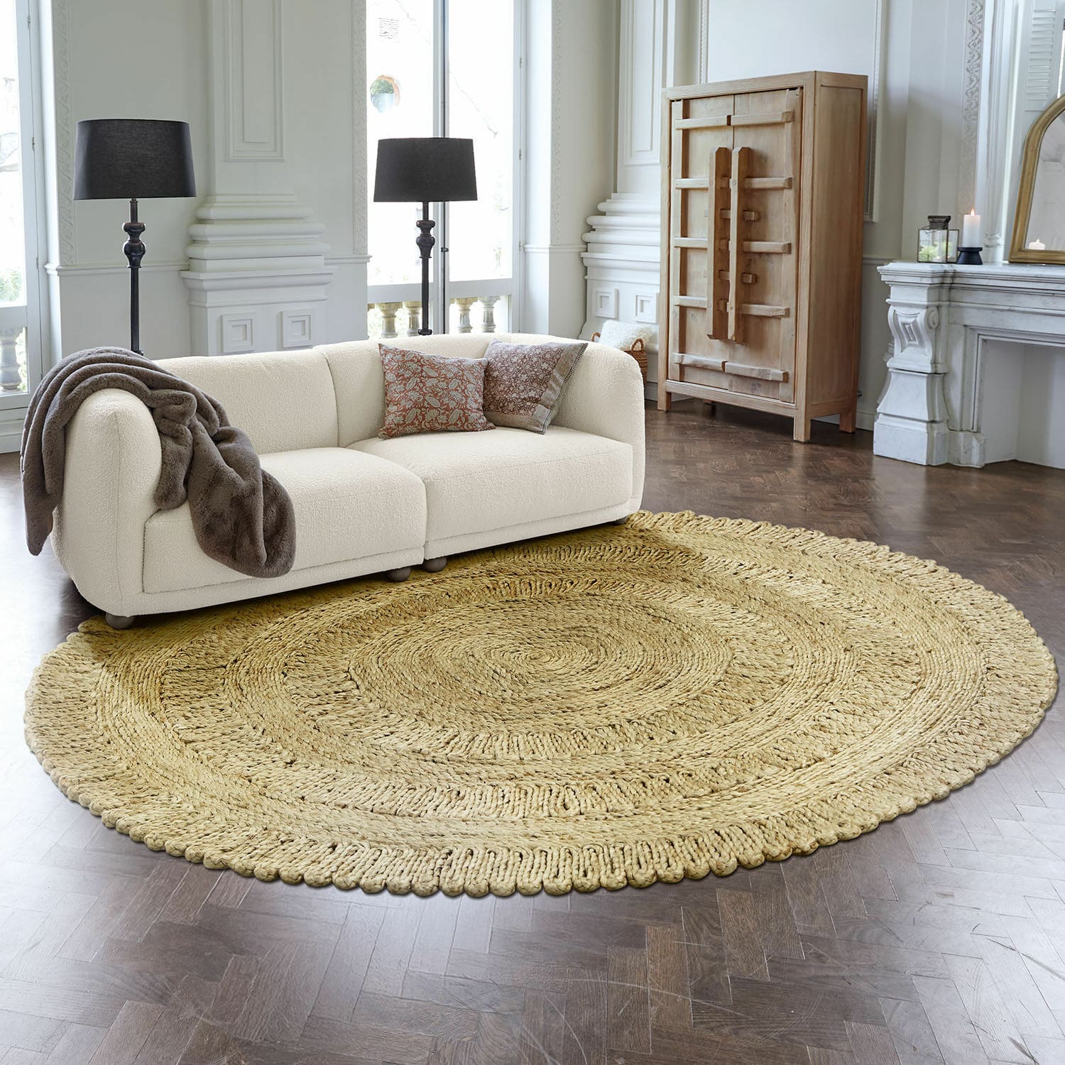Vloerkleed Arendel Ronde beige vloerkleed van natuurlijk materiaal in moderne woonkamer met witte bank en houten vloer
