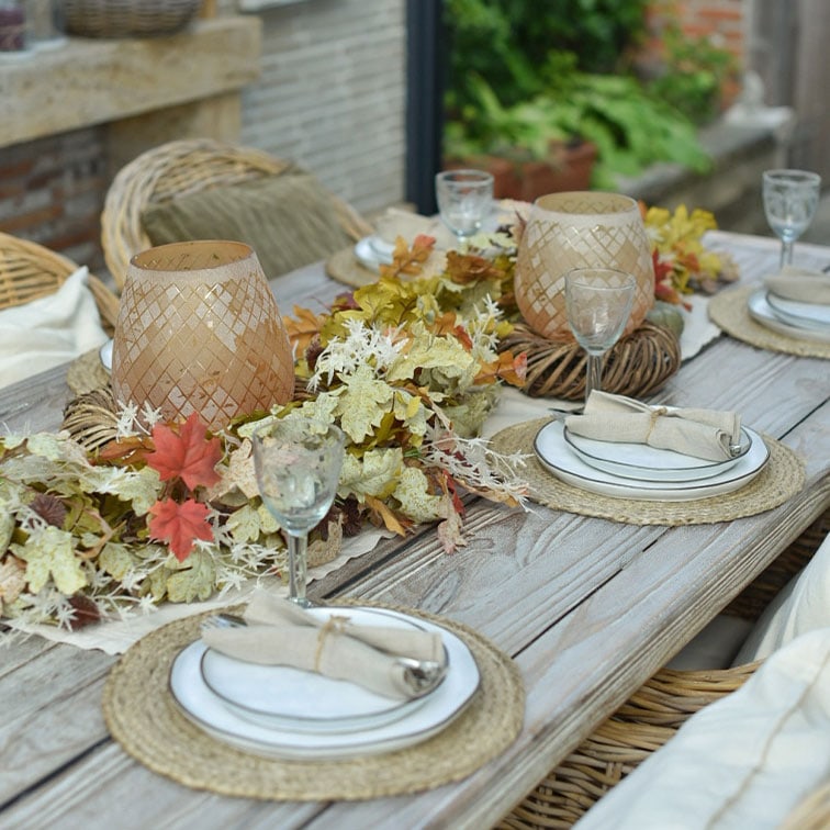 Rustieke houten tafel met natuurlijke bladeren en rotan lantaarns voor een gezellige sfeer