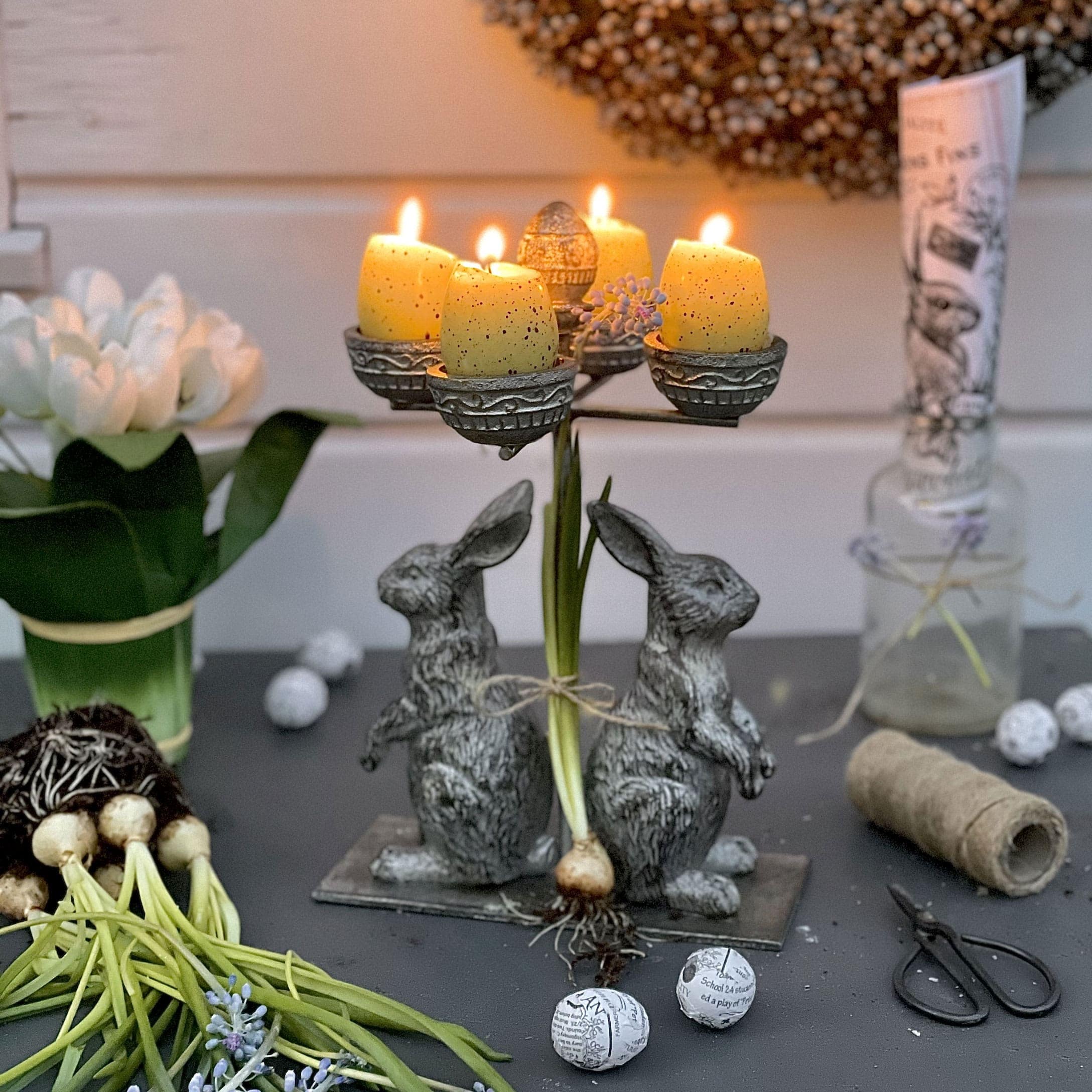 Metalen kandelaar met twee konijnen en gele kaarsen voor lentetafeldecoratie