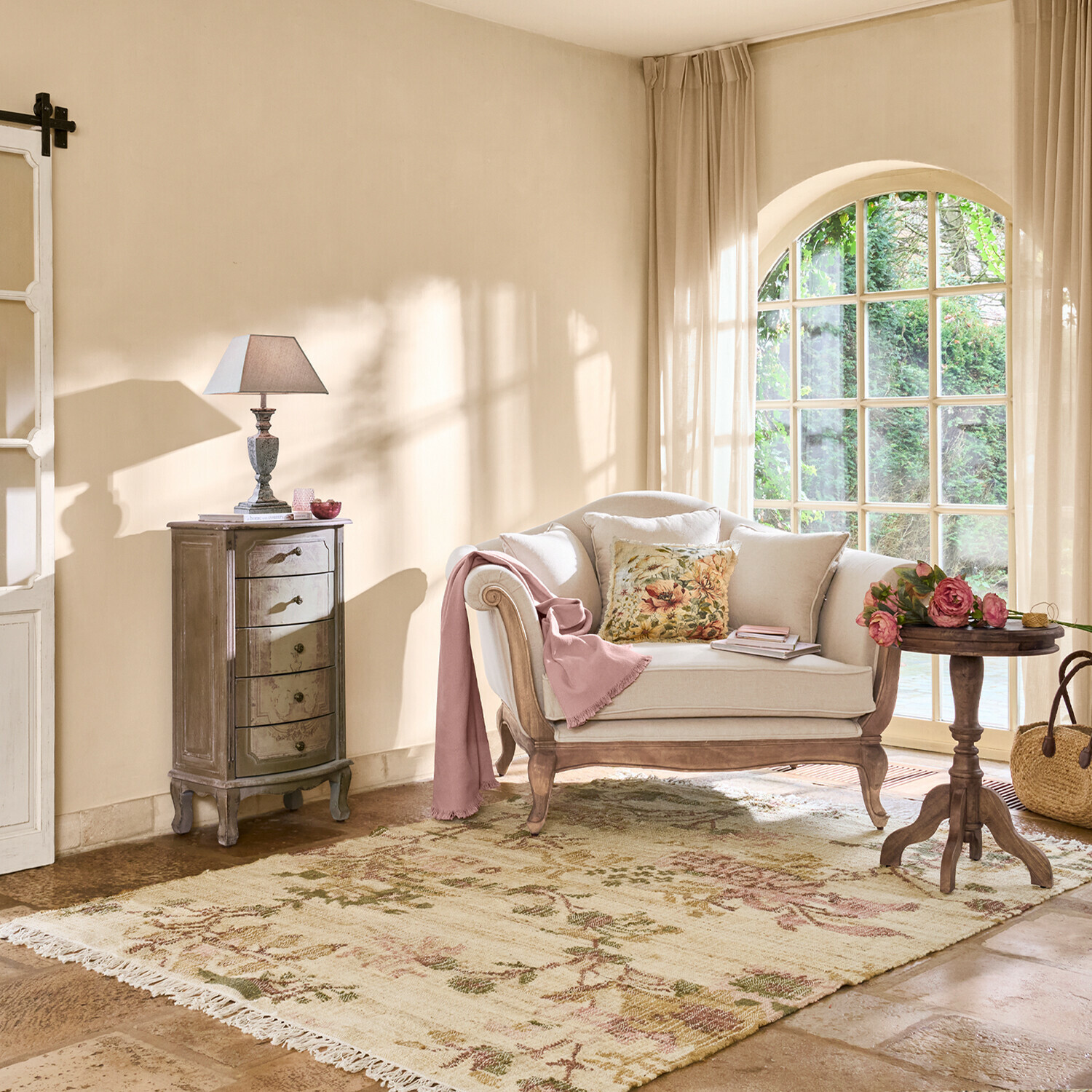 Gezellige woonkamer met beige bank, houten tafel, lamp en vloerkleed met bloemmotief