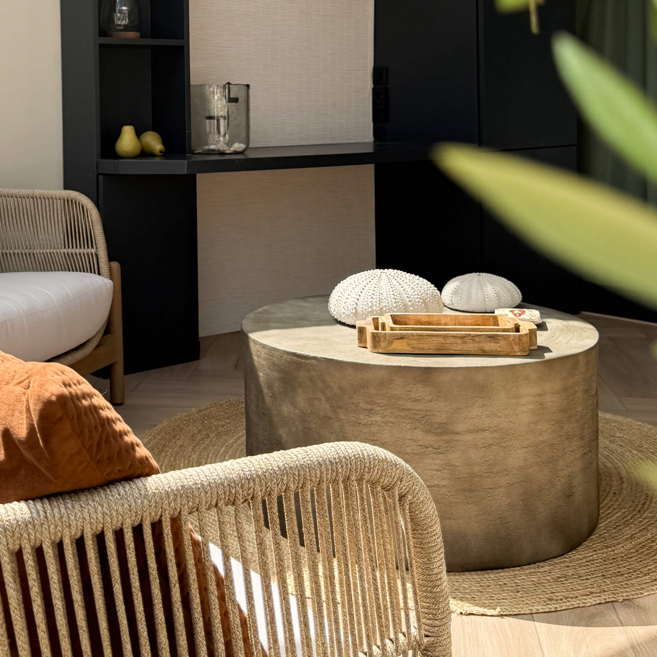 Ronde salontafel van beige beton op een ronde natuurlijke vezelmat in een moderne woonkamer