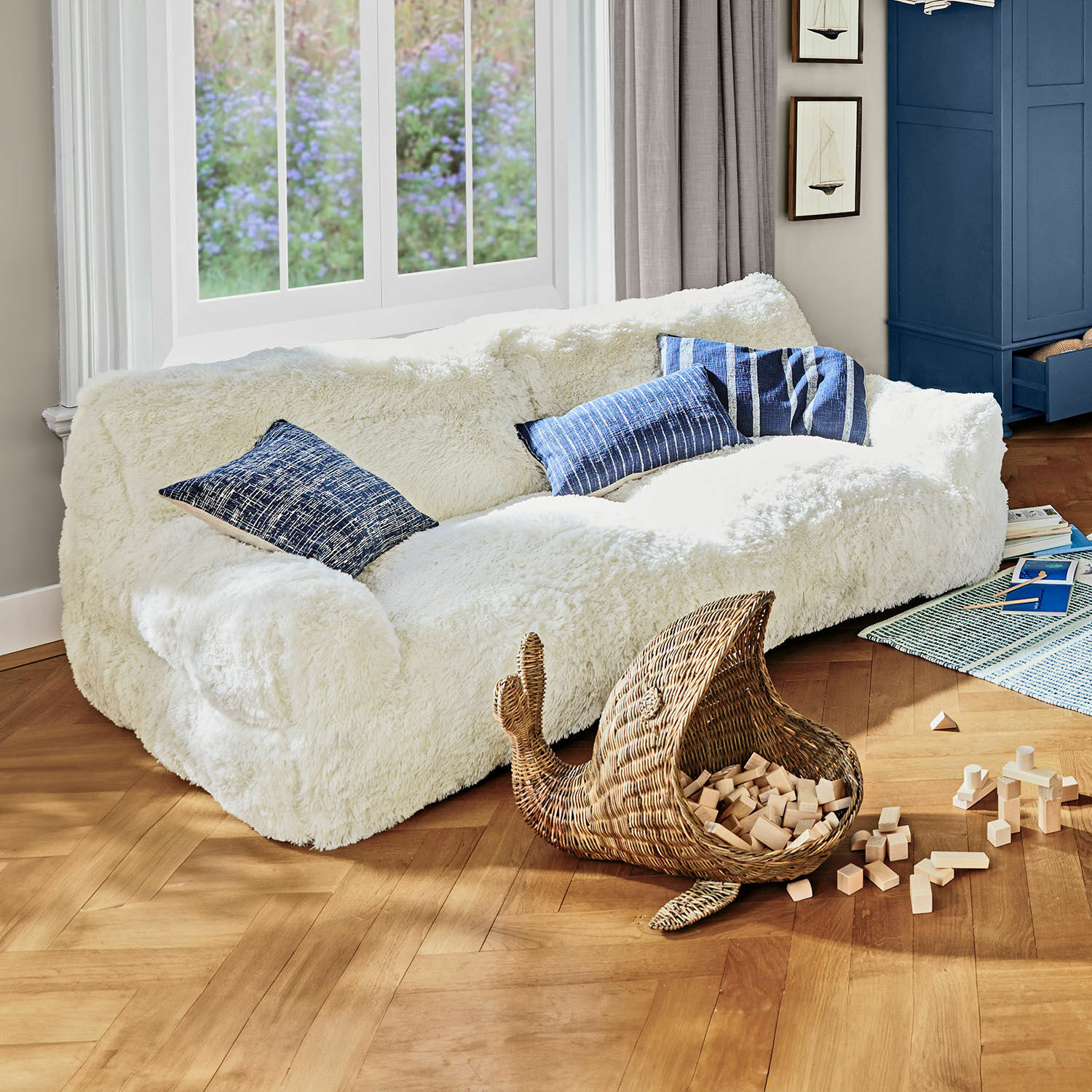 Kinderbank Cerveteri Witte, zachte pluche bank met blauwe kussens in lichte woonkamer met houten vloer