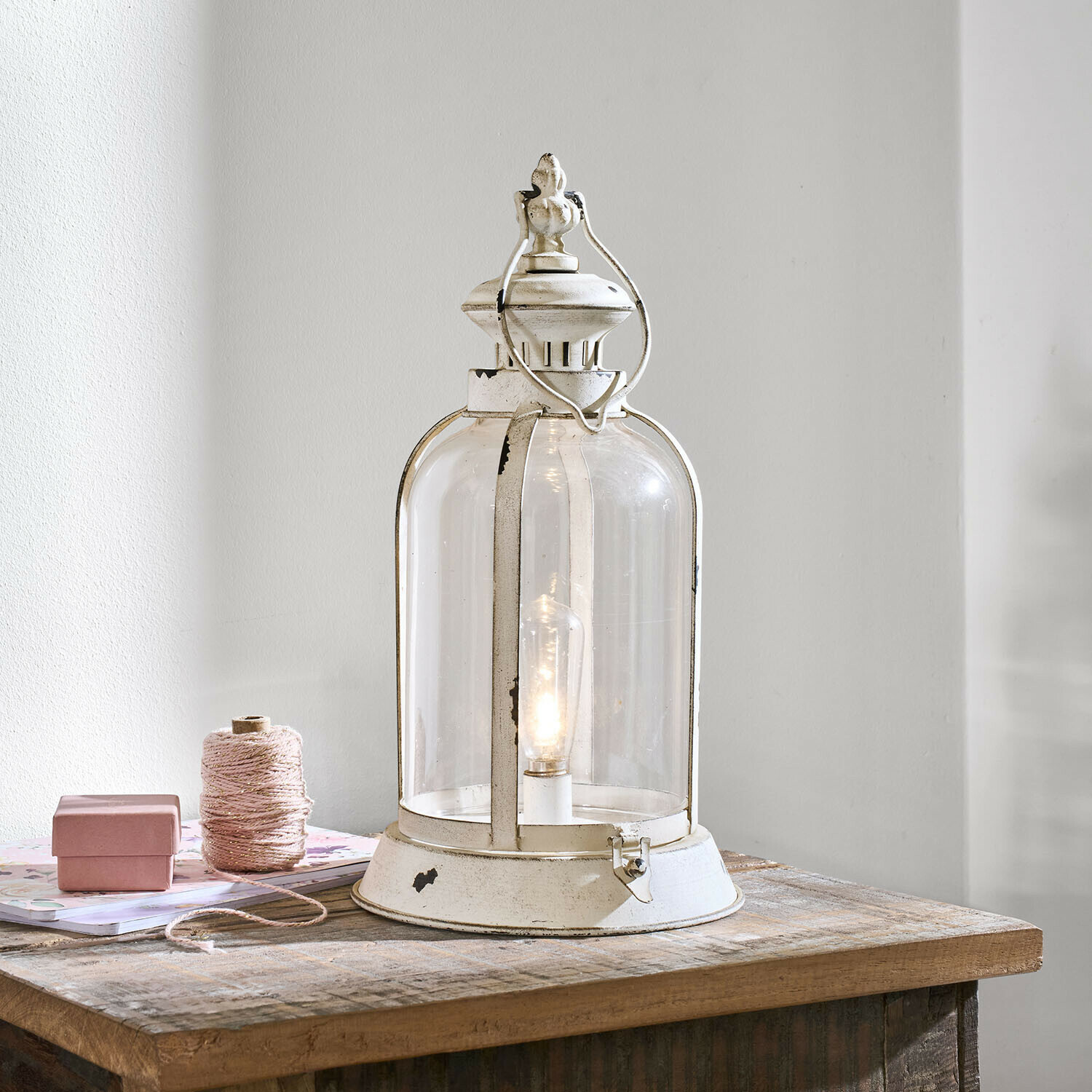 Witte metalen lantaarn met helder glas en gloeilamp op houten tafel, interieurdecoratie