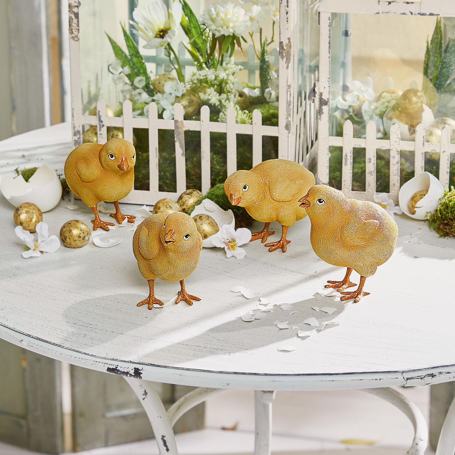 Kuiken set van 4 Wendolin Vier gele decoratieve kuikens op een witte tafel met paasdecoraties en nep-eieren